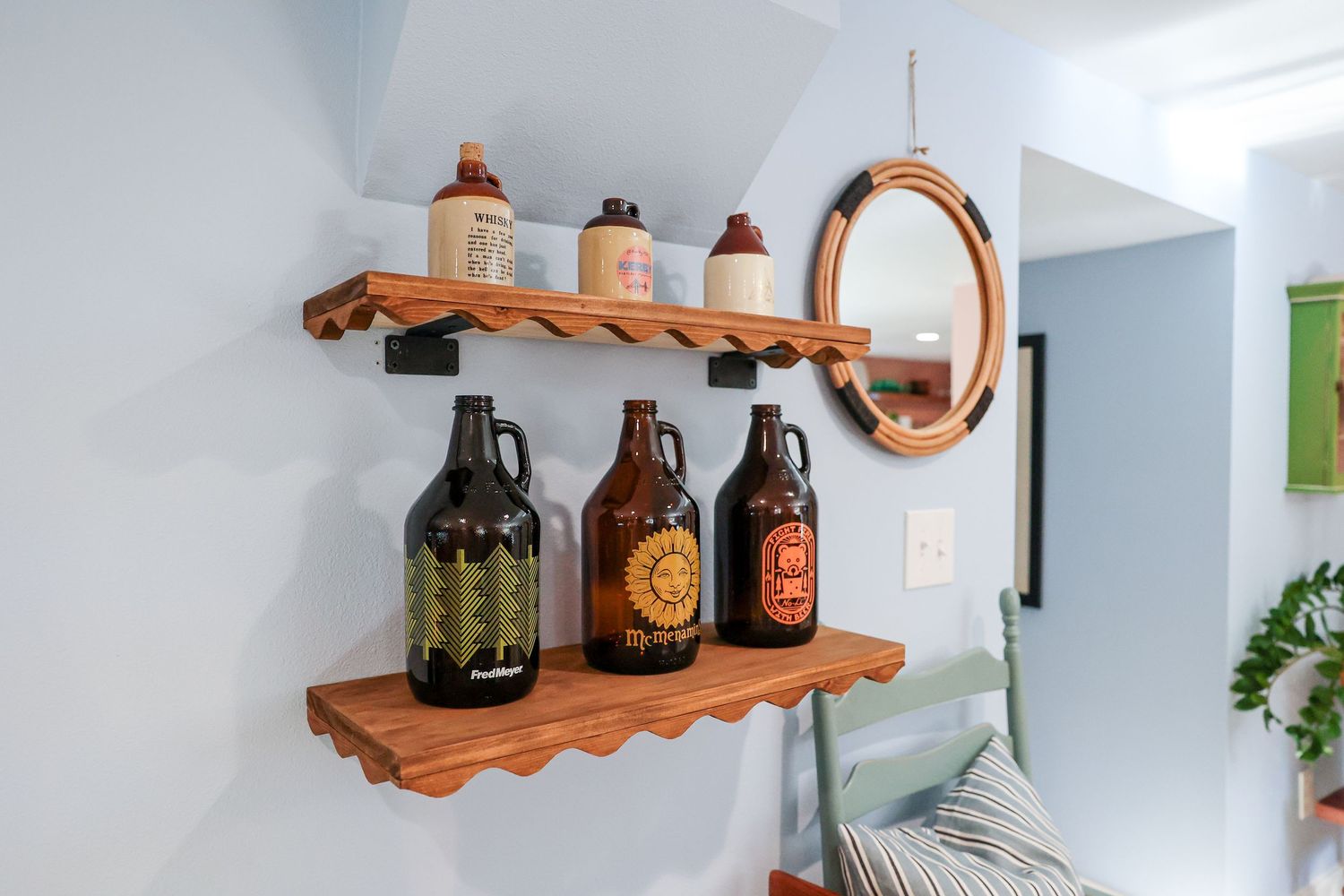 Wooden floating shelves displaying beer growlers and decorative mirror.