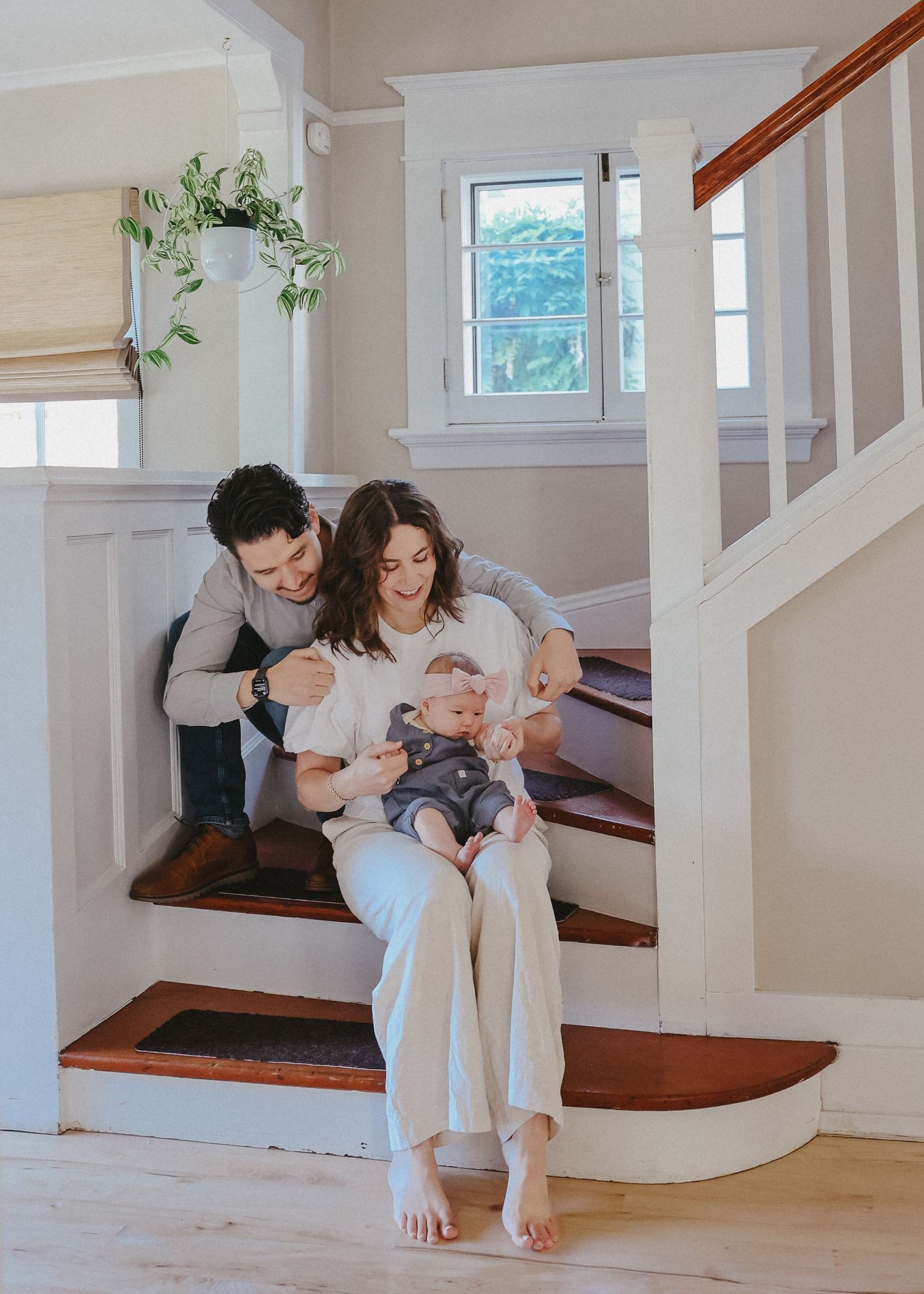 Intimate family moment captured on white interior staircase with natural light.