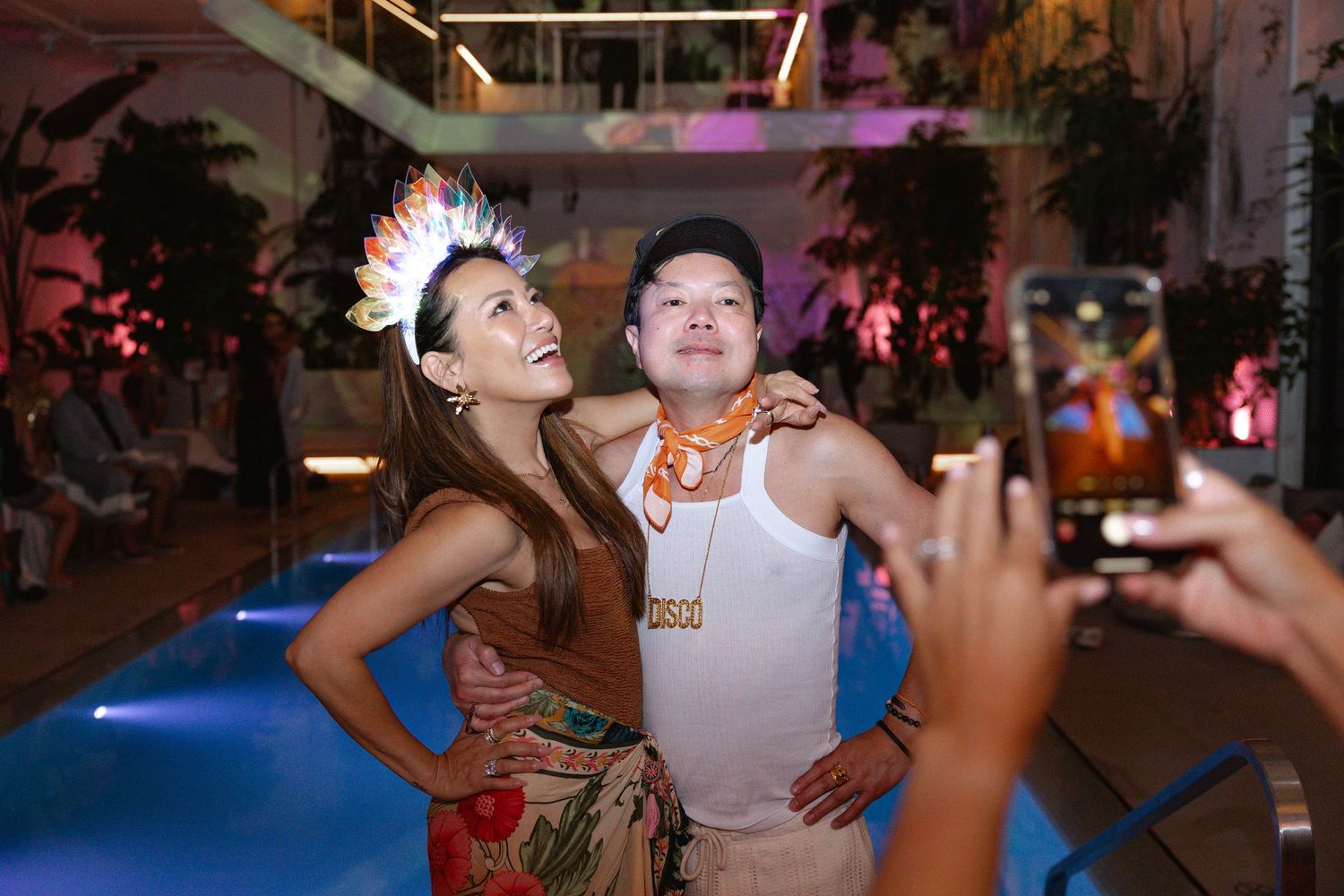 People dancing and celebrating at a lively indoor party with colorful lighting and decorations.