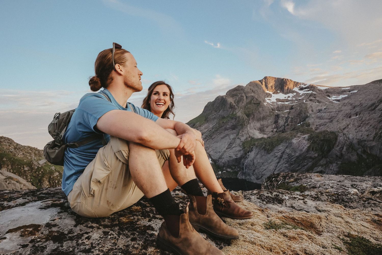 Hikers sitting and enjoying mountain views during golden hour in a scenic landscape.