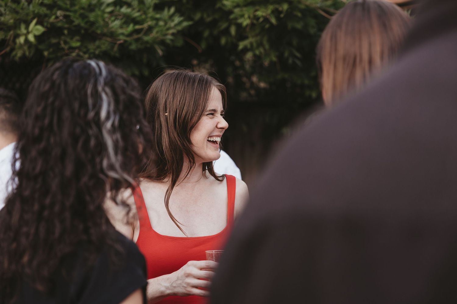A group of friends share a candid moment of laughter during an outdoor gathering.