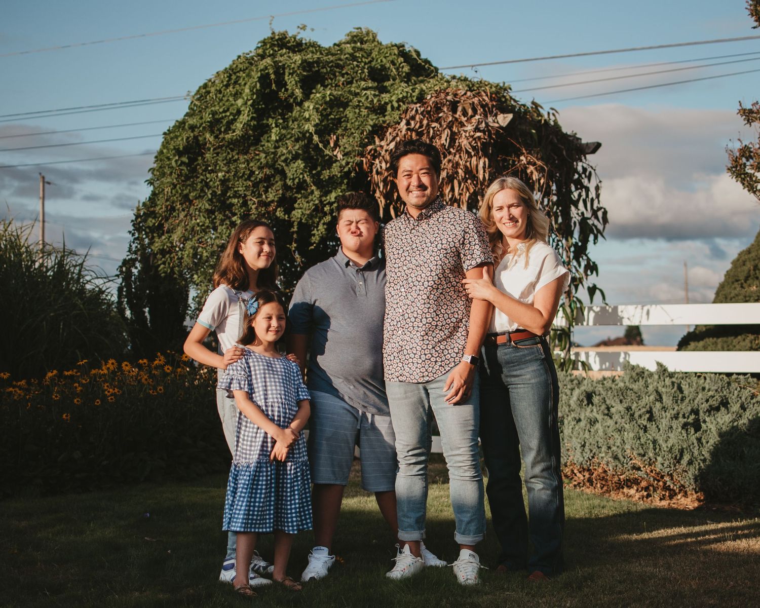 Family members walking together through a grassy field at sunset holding hands and enjoying quality time outdoors.