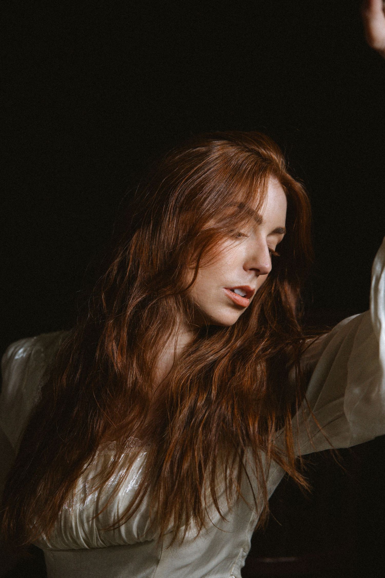 A series of moody portraits showing a person with flowing red hair against a dark background.