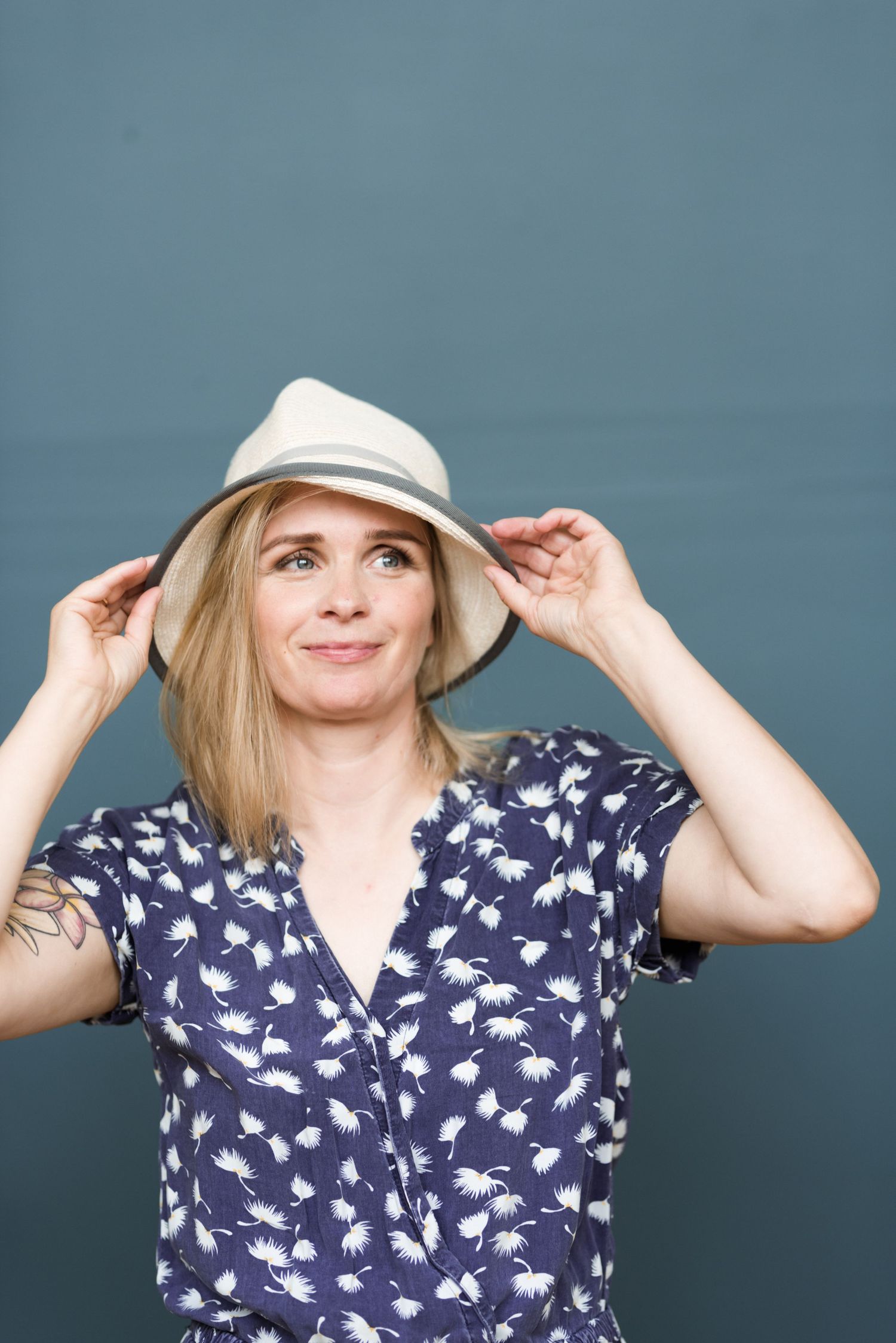 A sequence of photos showing someone in a navy floral print top adjusting a white baseball cap against a blue background.