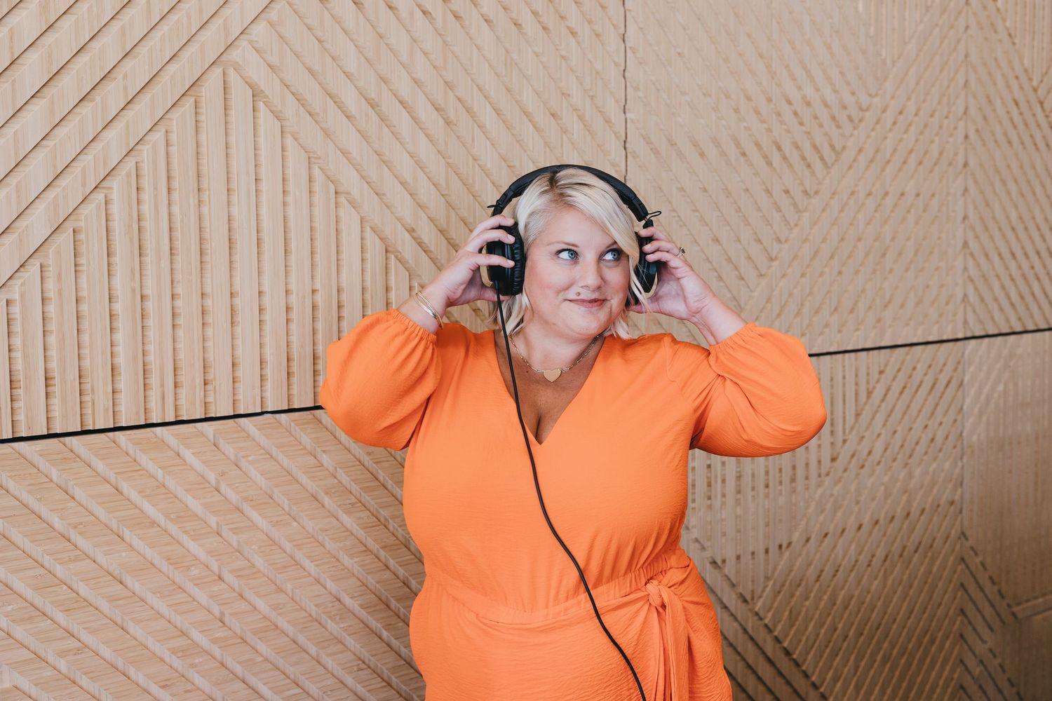 Someone in a bright orange sweater poses expressively against a beige wall in multiple connected shots.