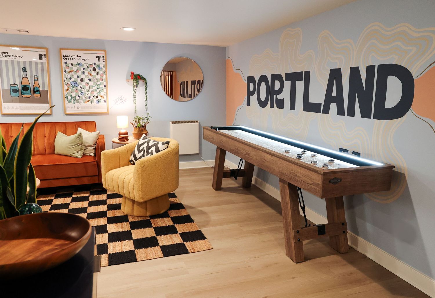Game room with shuffleboard table, orange sofa and black and white checkered floor.