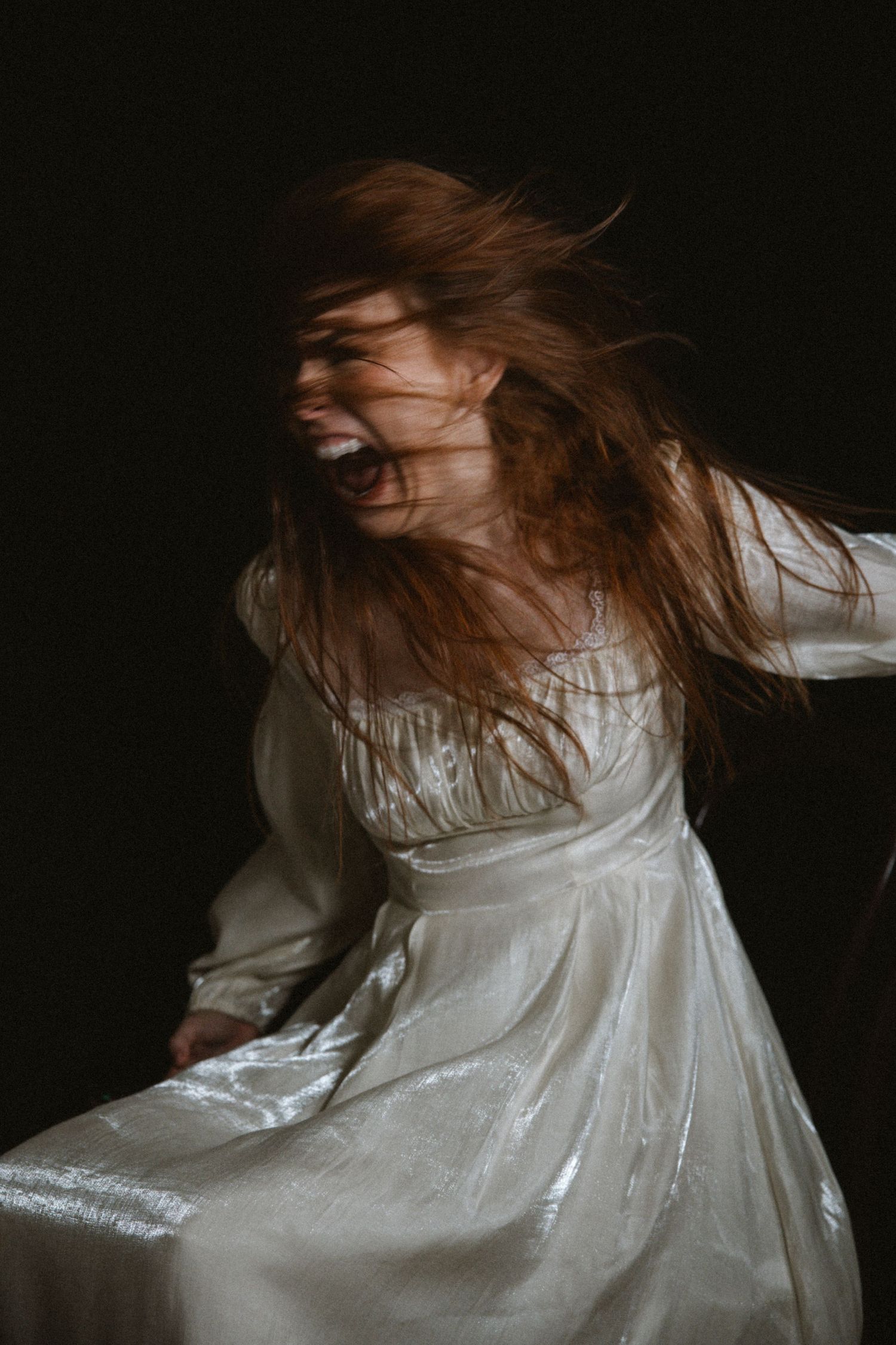 Dynamic motion shot showing flowing white dress and hair movement against black background.