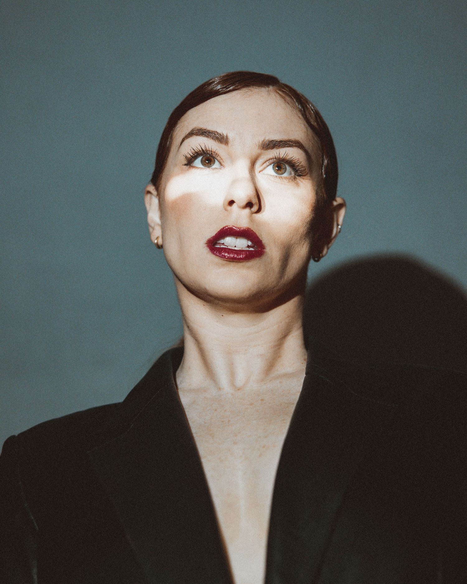 A dramatic fashion portrait series showing a model in red lipstick against a moody blue-gray background.