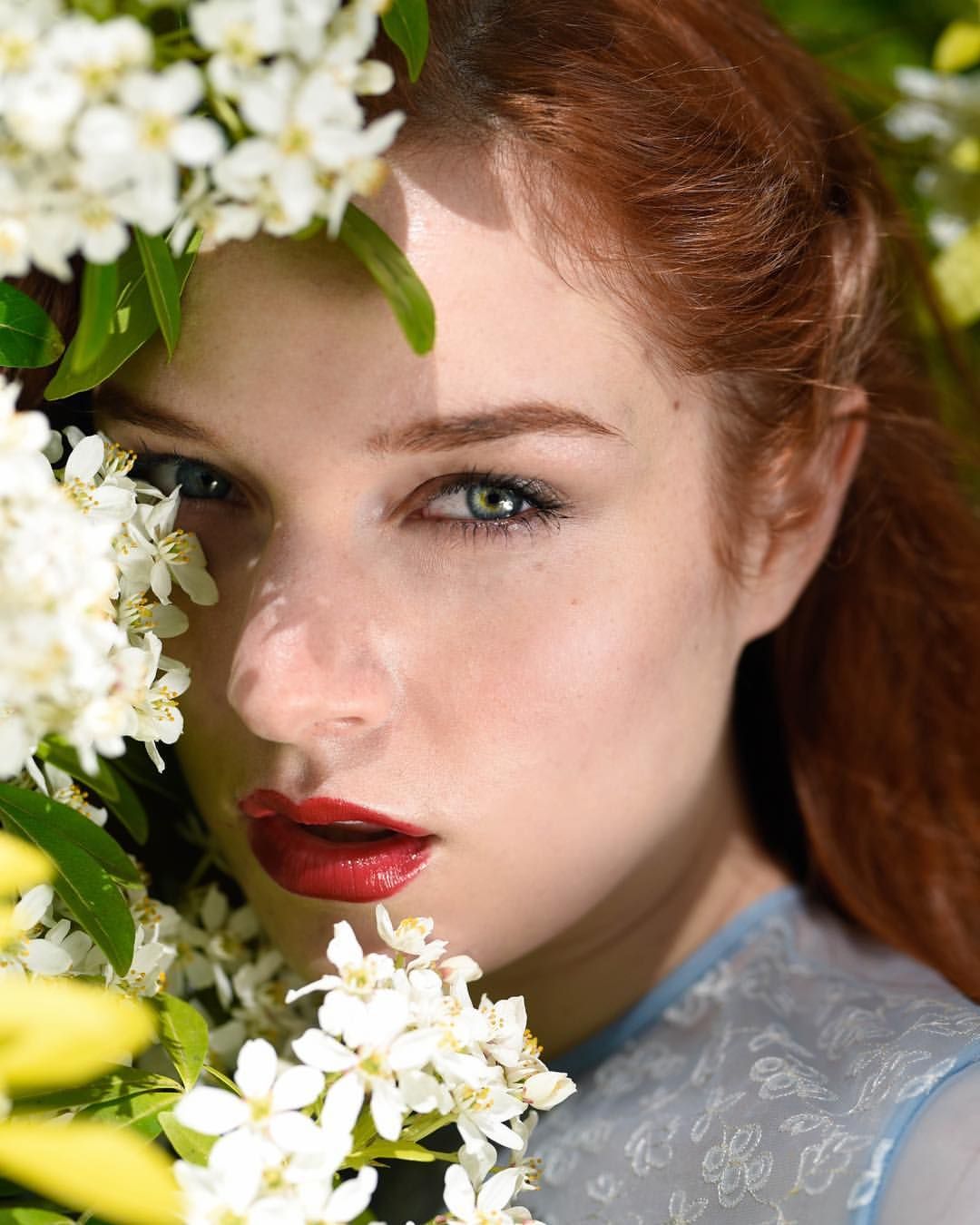 Ethereal beauty portrait with white spring blossoms and red lipstick.