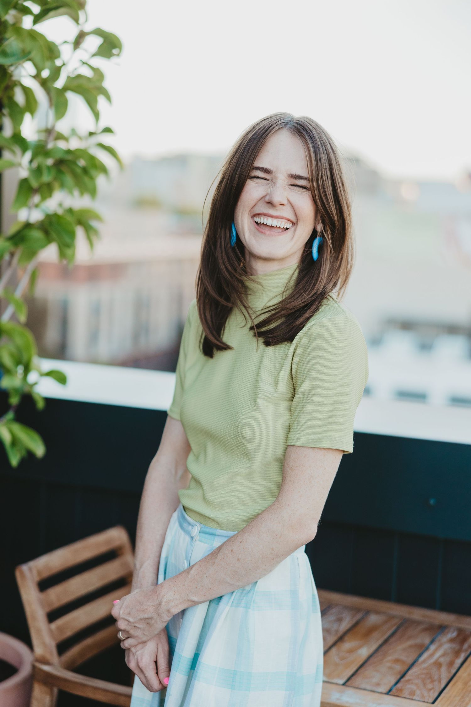 Candid portrait of person in lime green shirt and plaid skirt on outdoor patio.