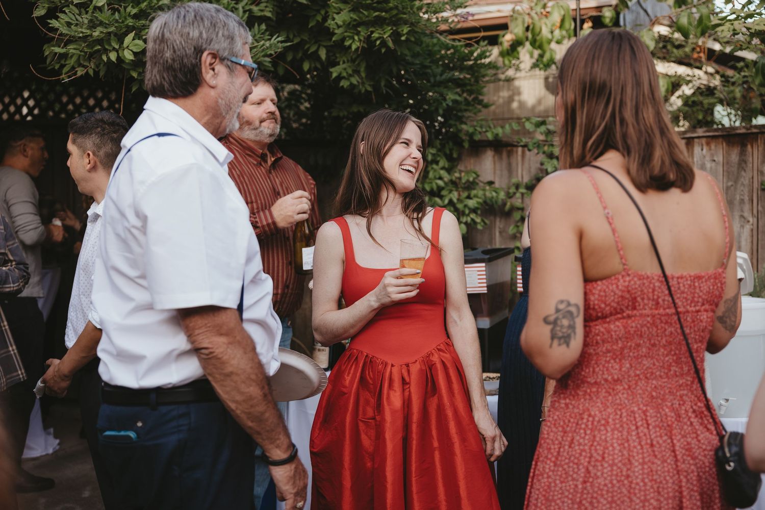 Wedding party in coordinated red and white outfits gathered outdoors at a summer celebration.