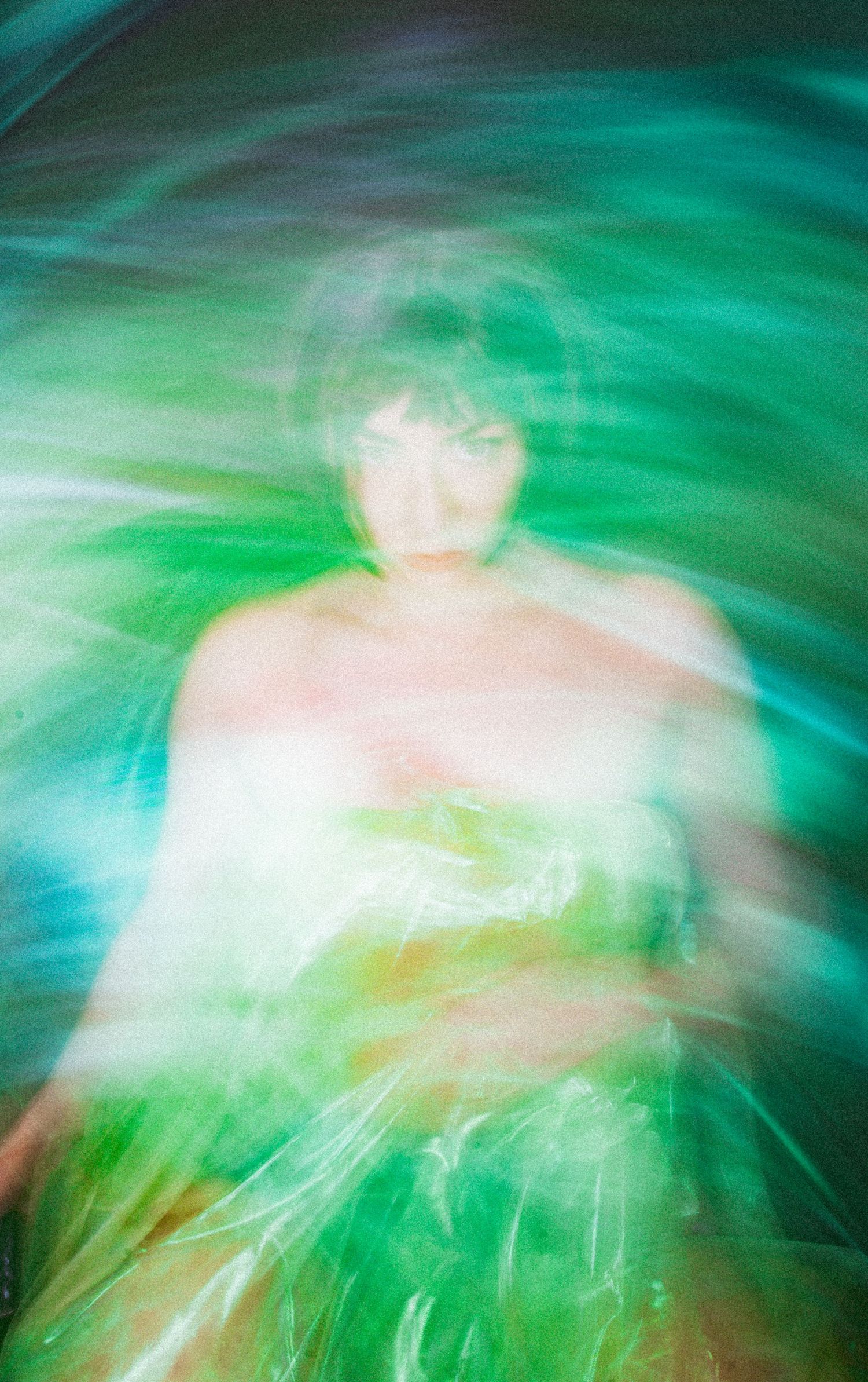 Abstract long exposure photograph creates ethereal swirls of turquoise and green light with blurred motion effects.