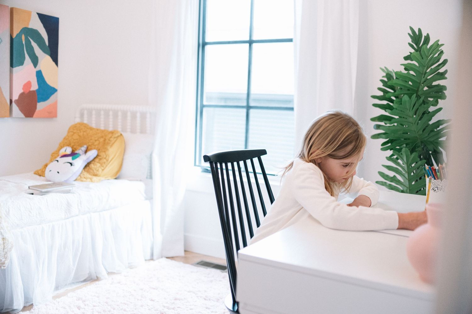Bright white bedroom with modern abstract artwork and potted plants.