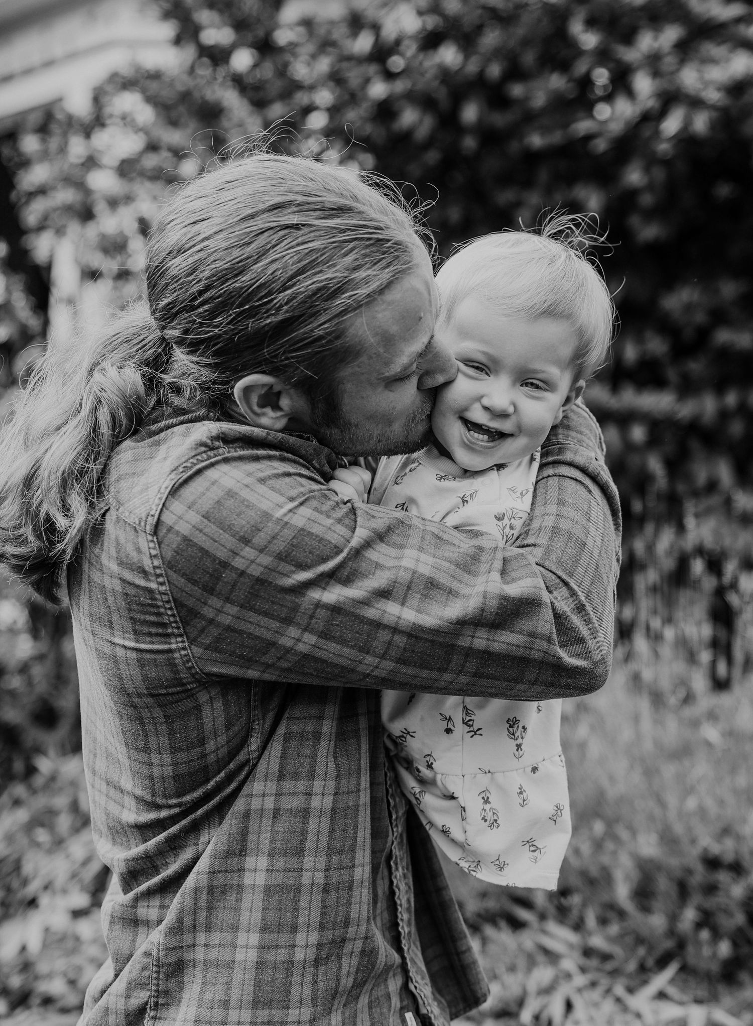 Sweet candid black and white moment of affection and laughter outdoors.
