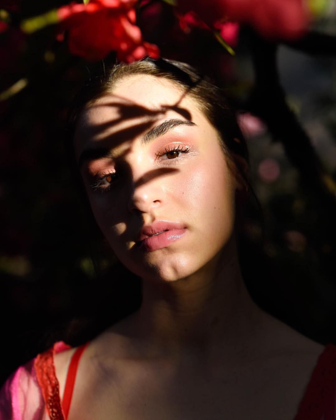 Artistic portrait with dramatic shadows and red floral elements.