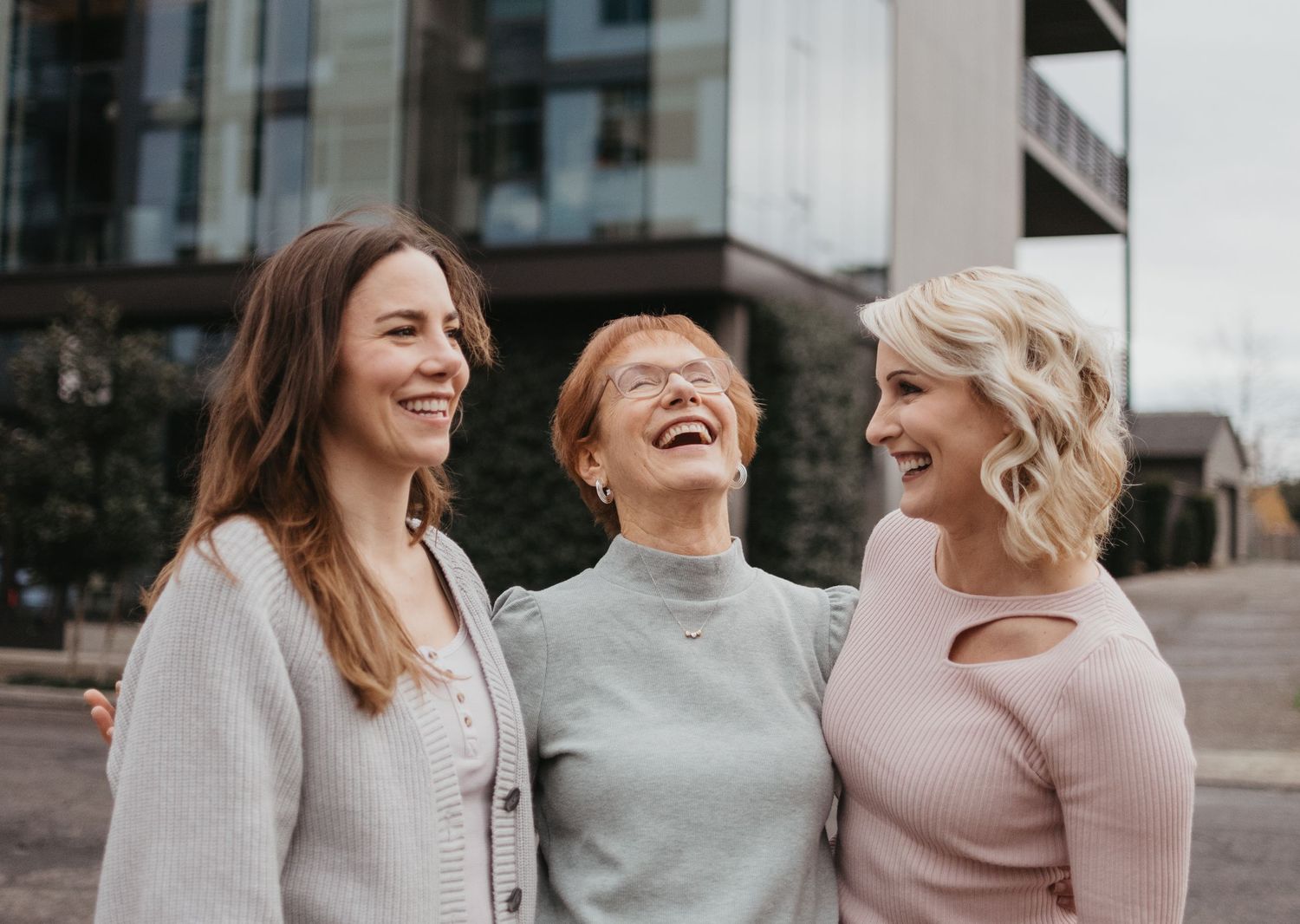 Three friends sharing genuine laughter against urban backdrop.