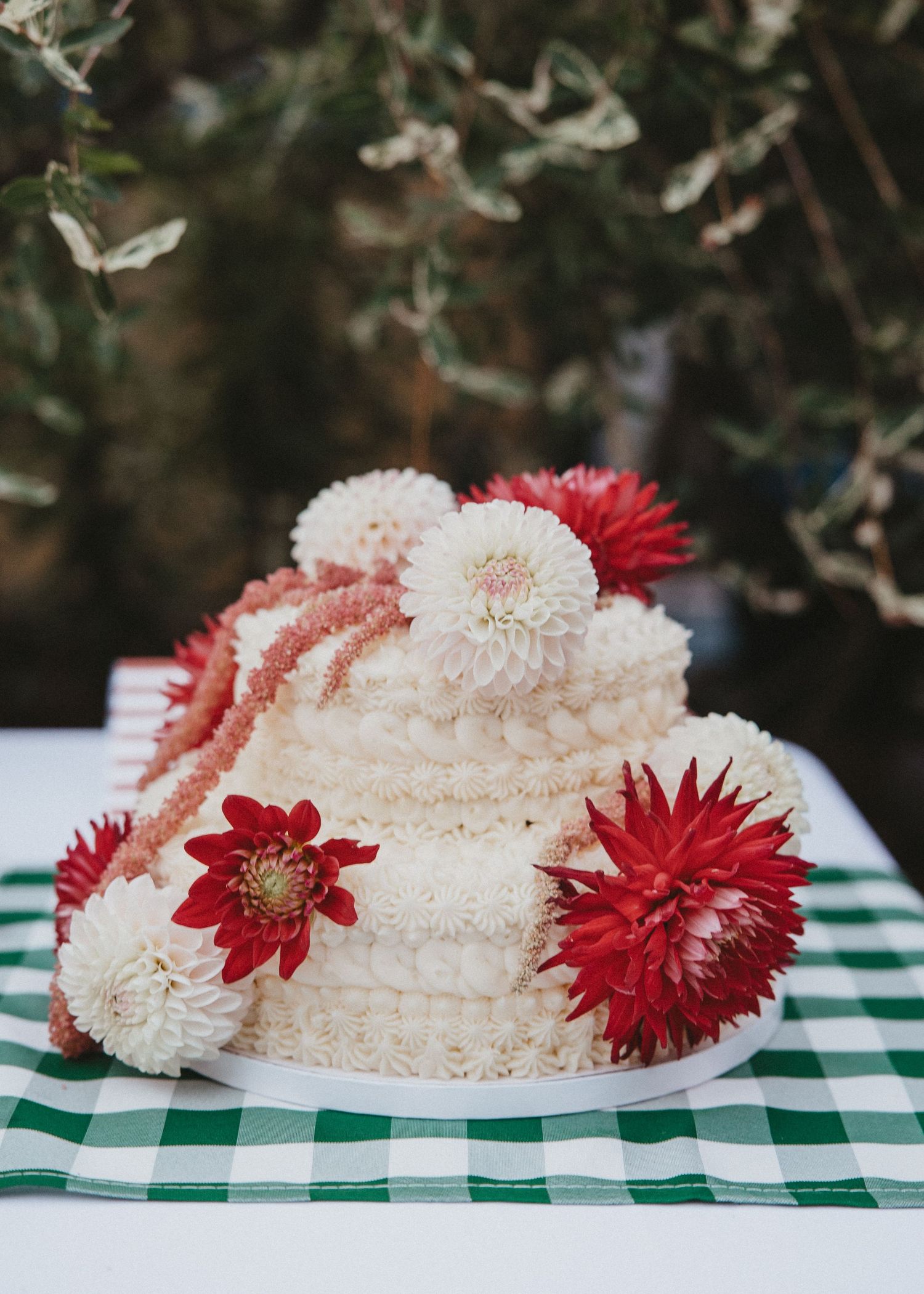 White and red dahlia flowers arranged on a green checkered tablecloth create an elegant table centerpiece display.