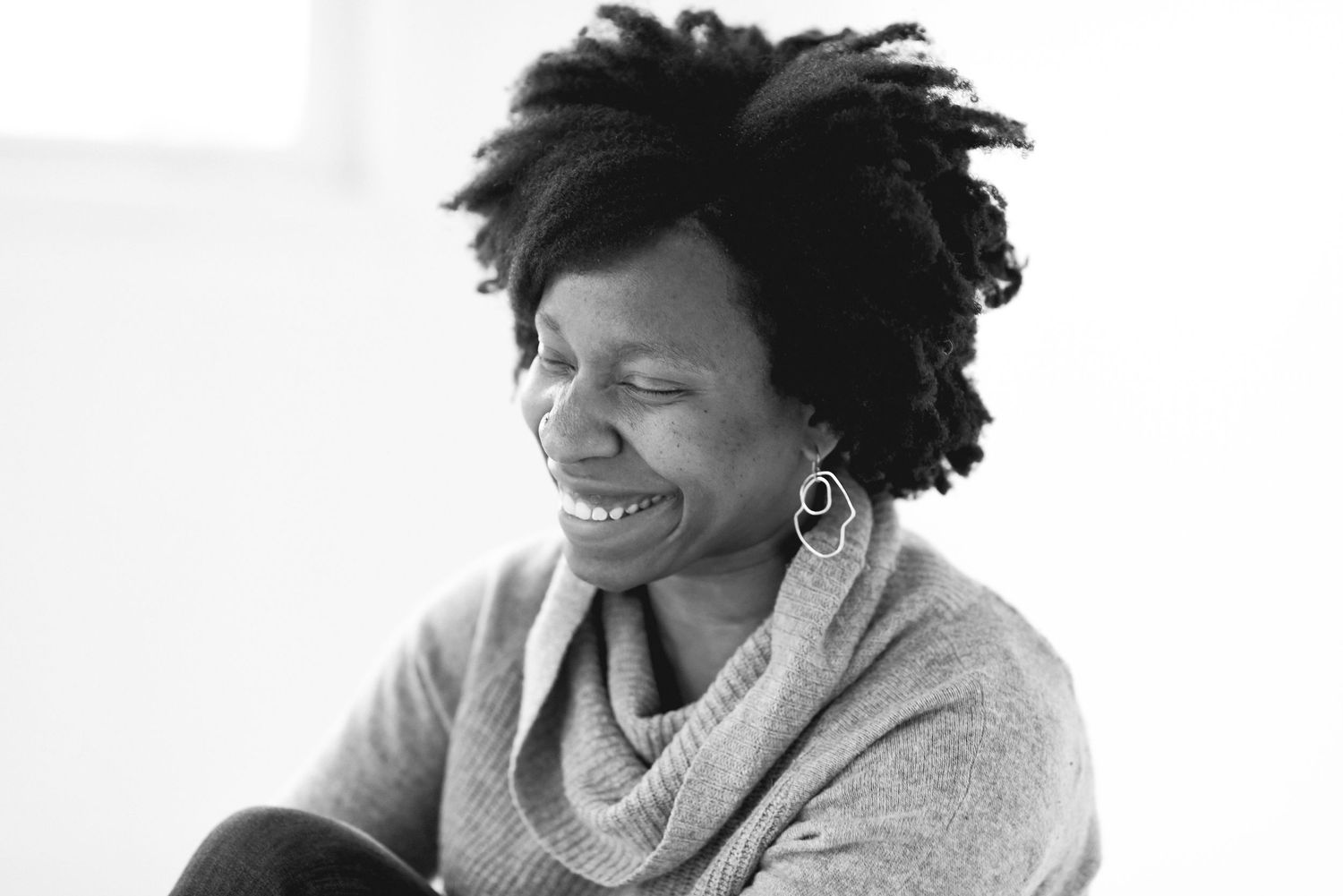 Two people share a joyful laugh while sitting together in black and white photography.