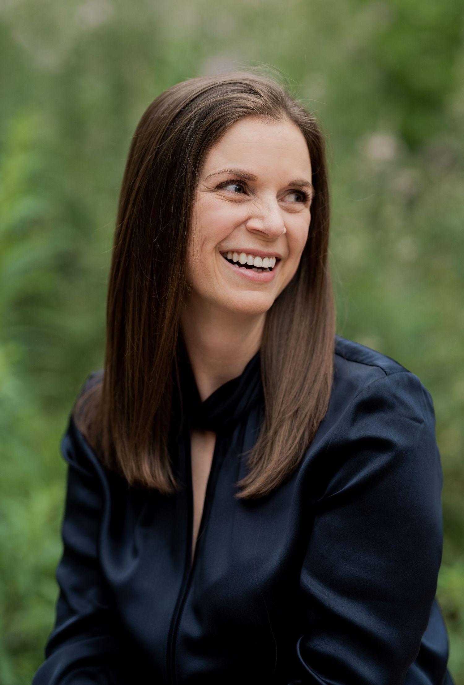A series of five professional headshots showing someone in a black blazer against a blurred green outdoor background.