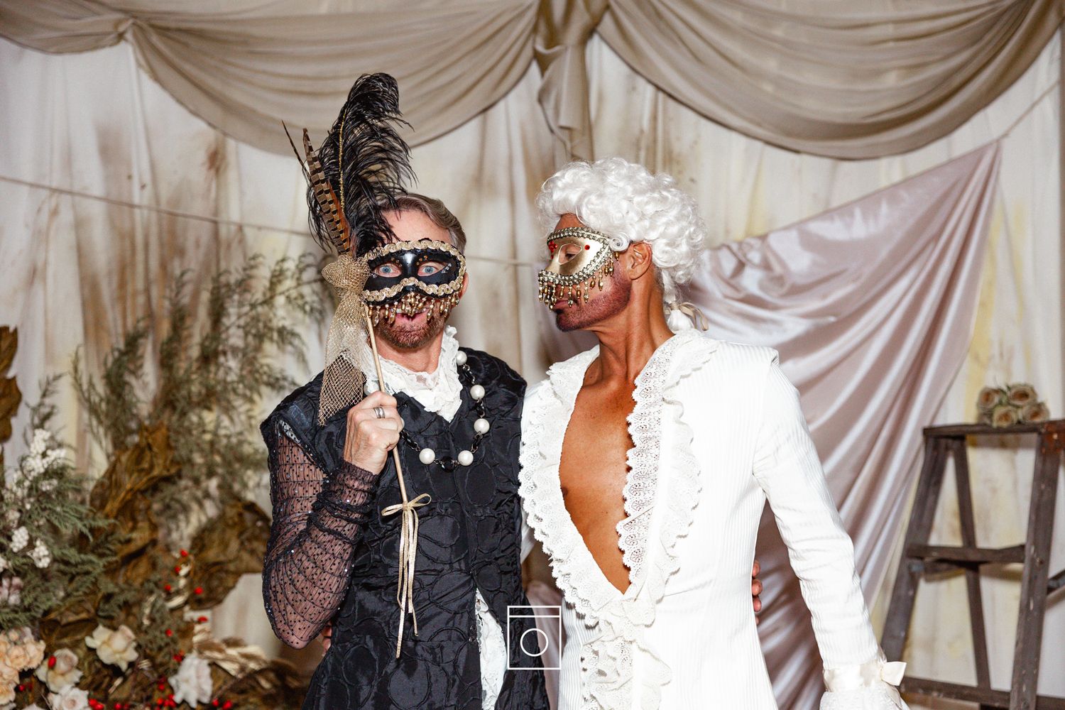A couple shares a joyful moment during their wedding celebration with draped fabric decor in the background.