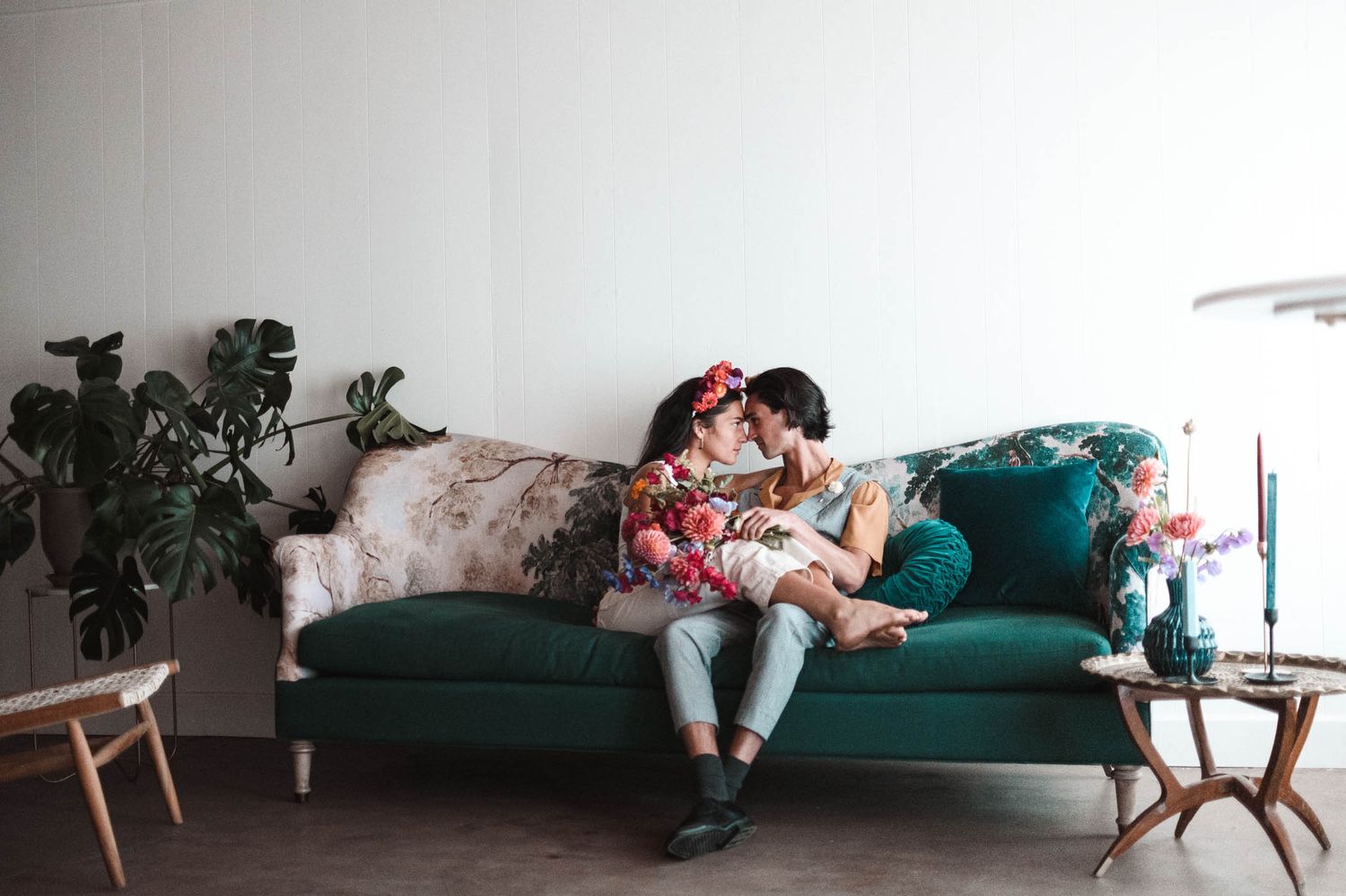 A romantic couple shares an intimate moment while sitting together on a green couch.