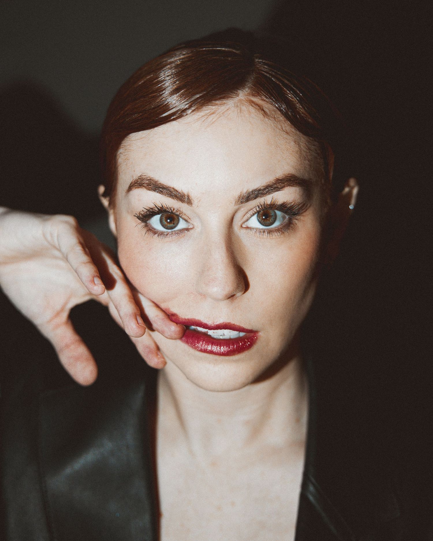 A dramatic series of close-up portrait shots showing red lipstick and expressive eyes in moody lighting.