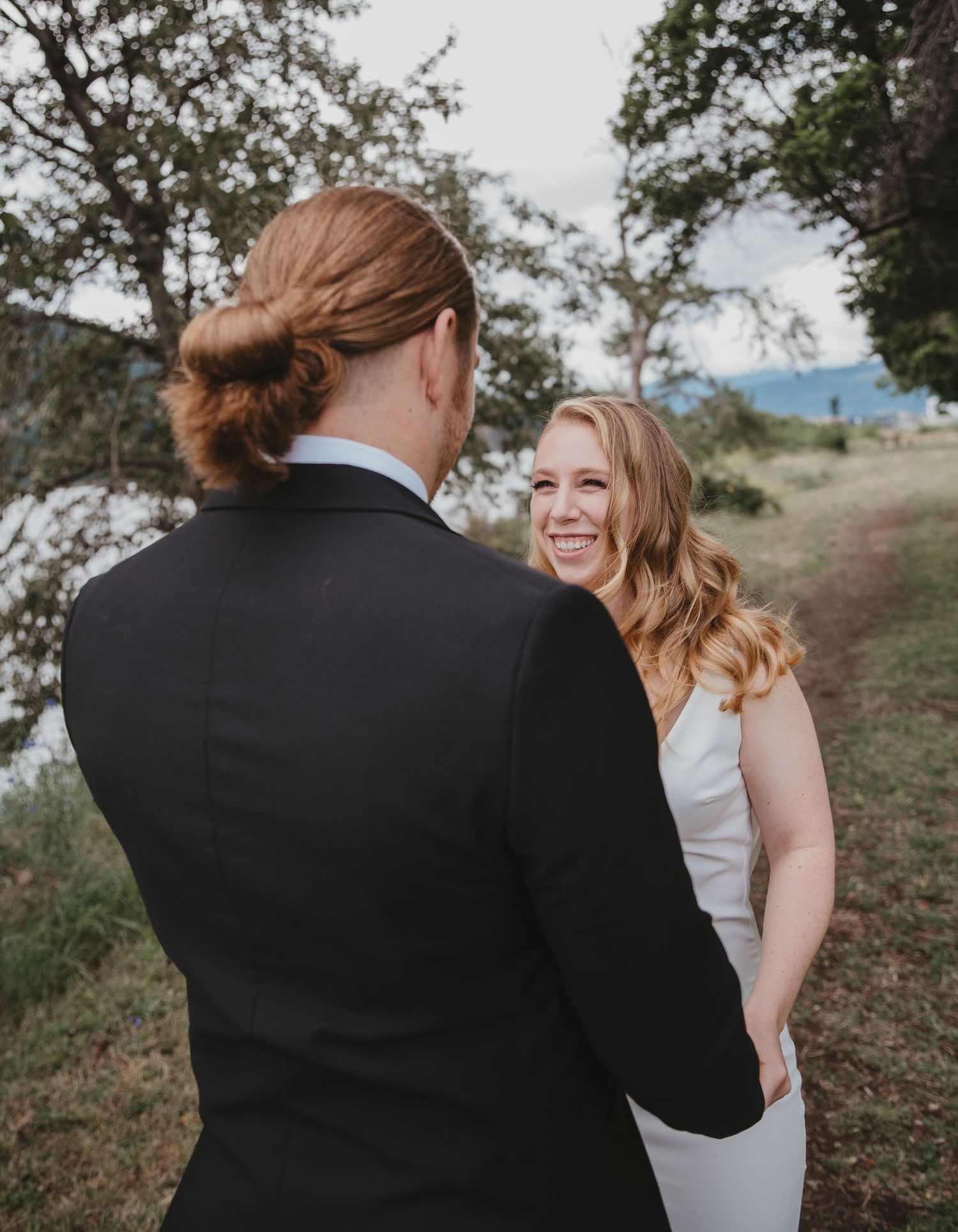 A candid moment between a couple at an outdoor wedding with nature in the background.