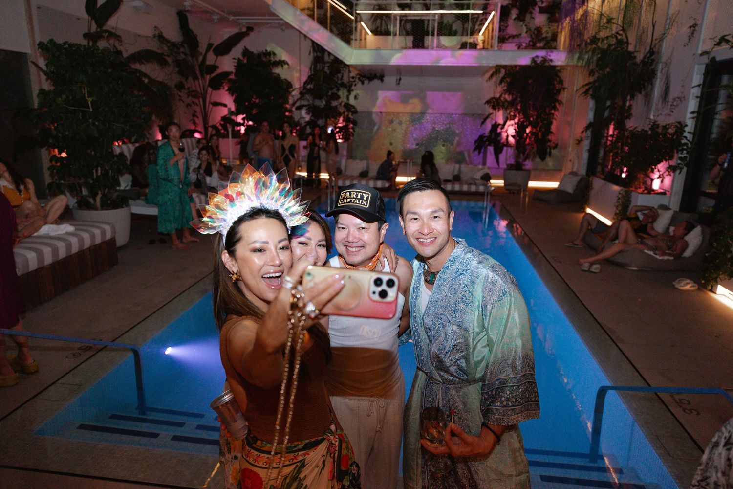 People dancing and socializing at a dimly lit indoor event space with colorful lighting and decorations.