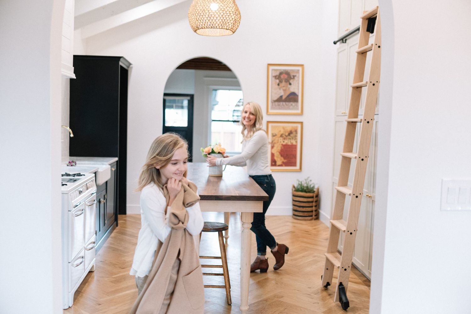 Kitchen interior with woven pendant light, wooden barstools and arched doorways.