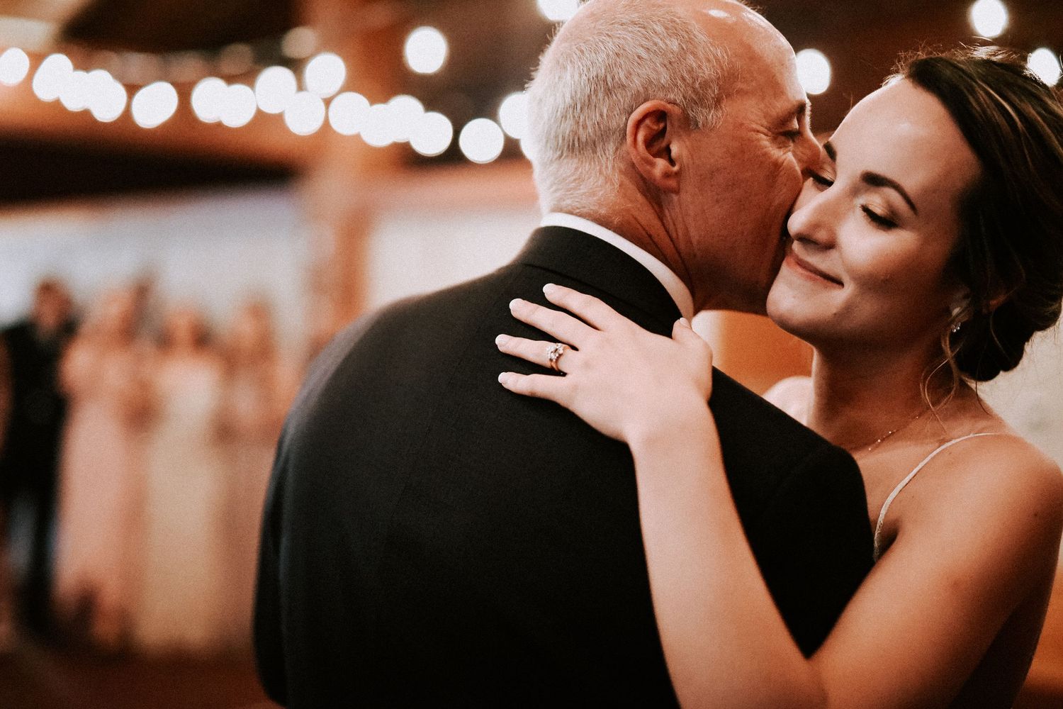 An emotional dance moment captured between two people at an indoor reception.