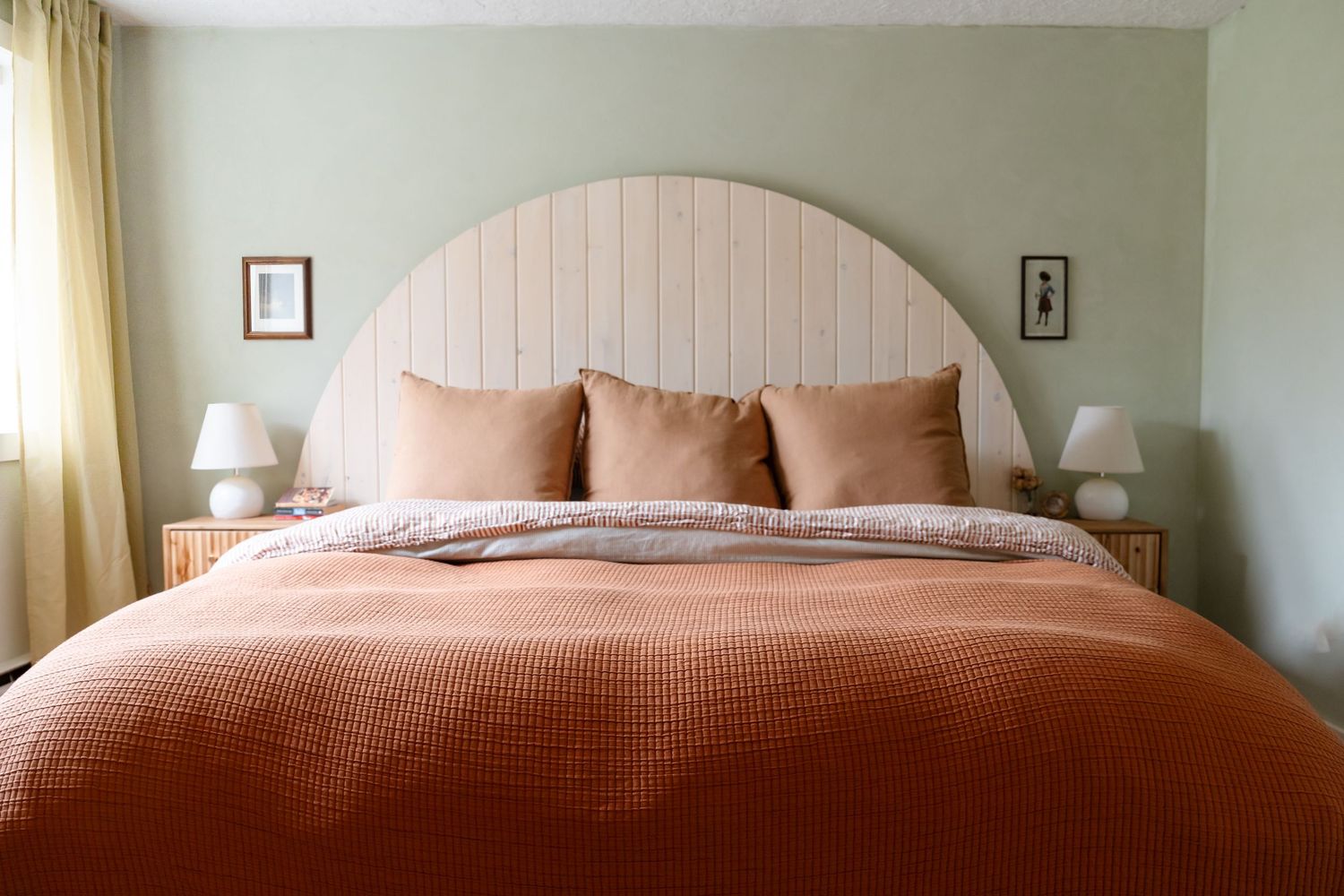 Minimalist bedroom with arched paneled headboard and terracotta bedding.