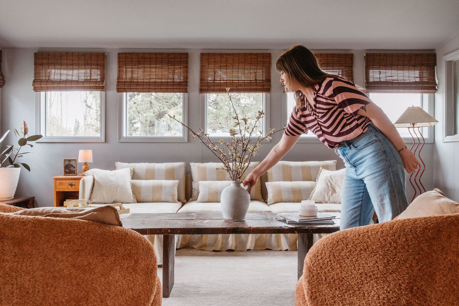 A cozy living room interior with brown furniture, natural light streaming through windows, and warm earth tones.