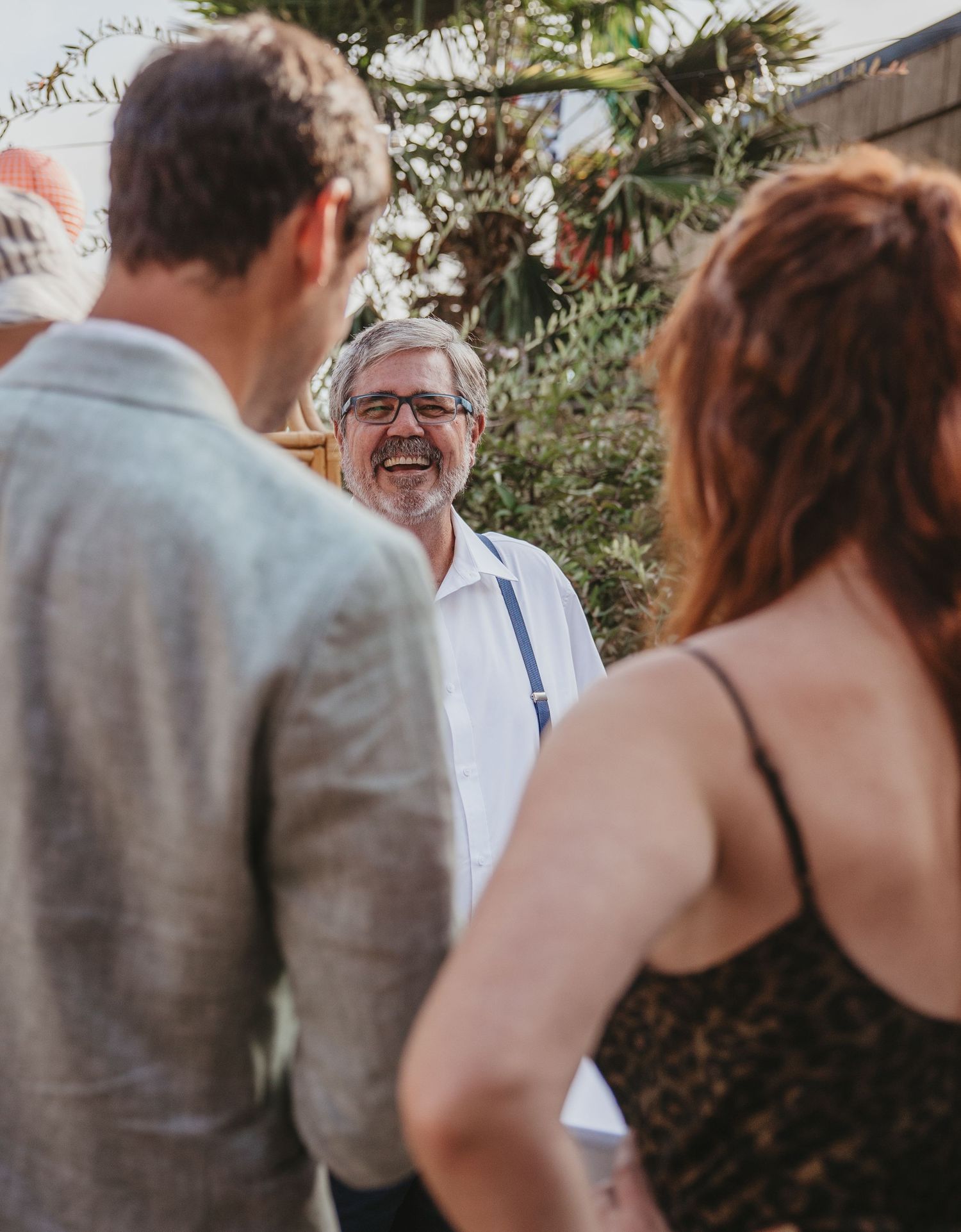A joyful moment captured during an outdoor wedding ceremony with palm trees in the background.