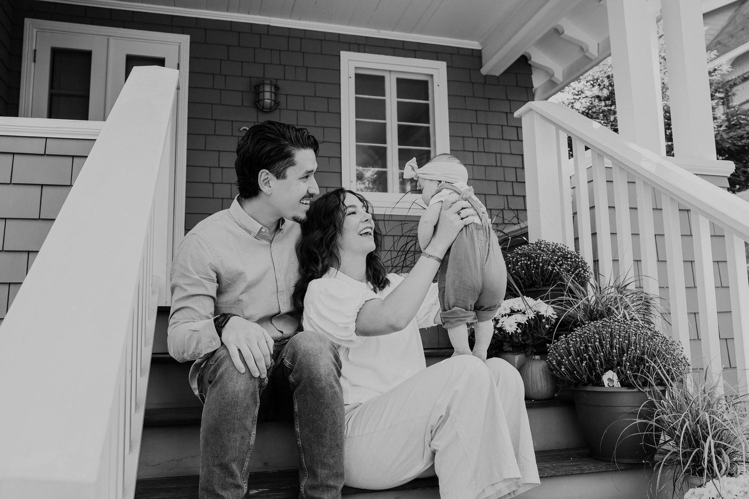 Black and white portrait of family moment on front porch steps of craftsman home.