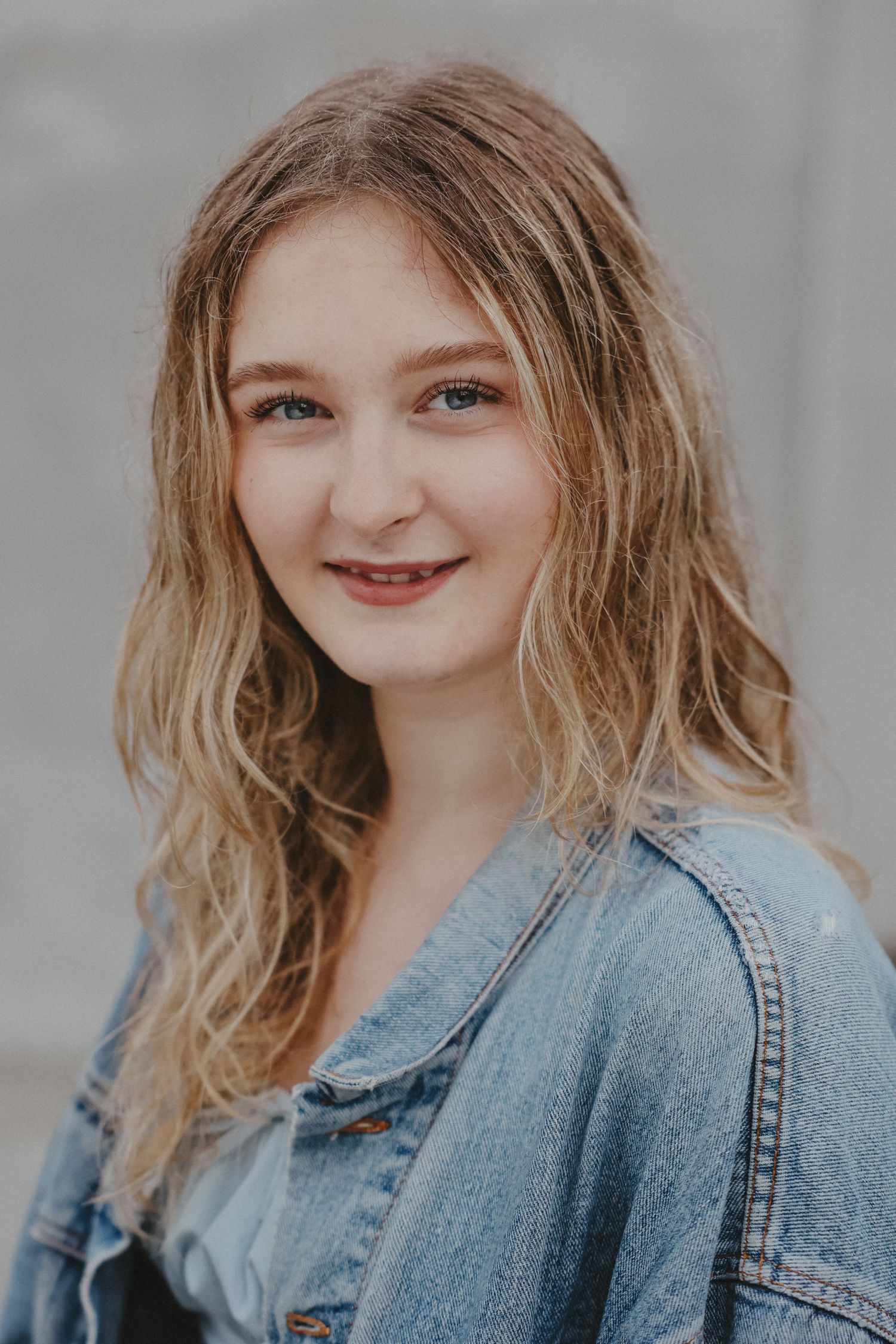 Close up portrait with denim jacket against neutral background.