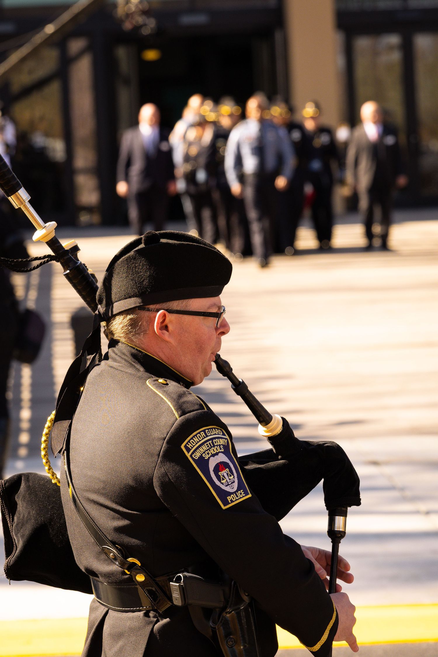 Police honor guard member performing ceremonial rifle movements during an outdoor service.