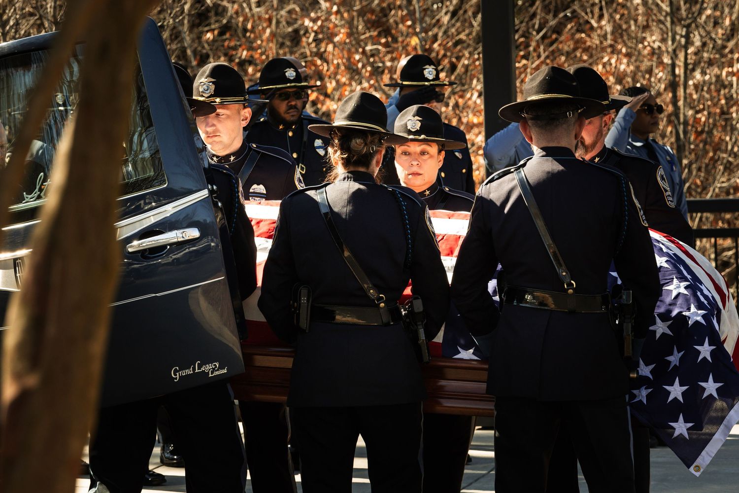 Police officers in dress uniforms stand at attention during a memorial service.