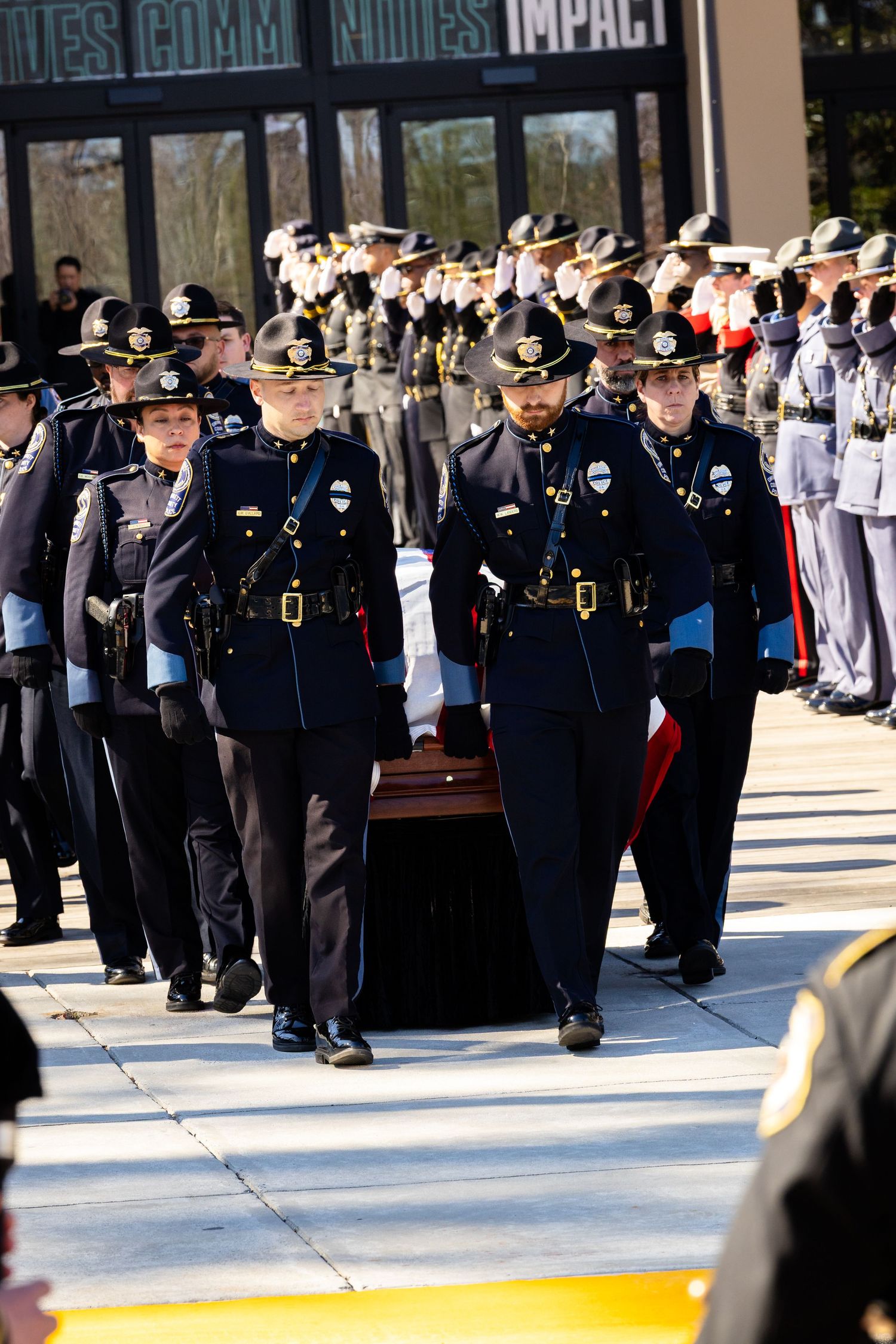 Police officers in formal uniforms march in formation during a ceremonial procession.