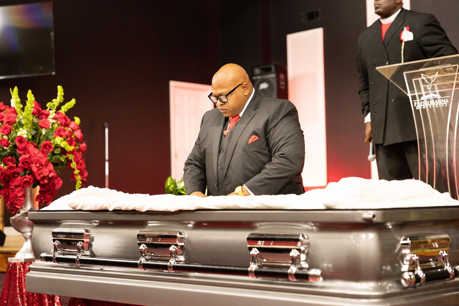 A formal event setup with dark stage lighting and floral arrangements near podiums.