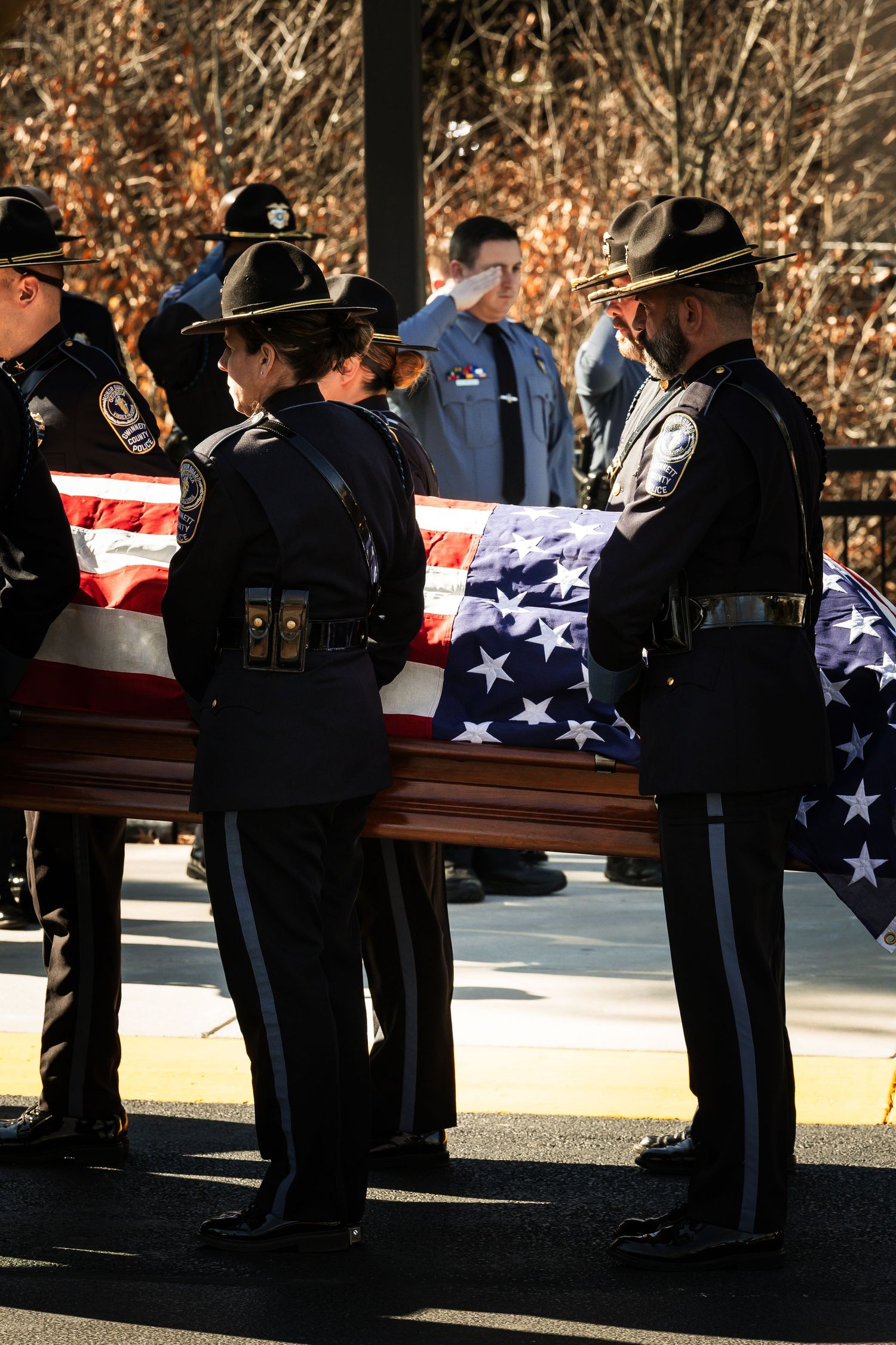 Honor guard members holding American flags while standing beside caskets during a memorial service.