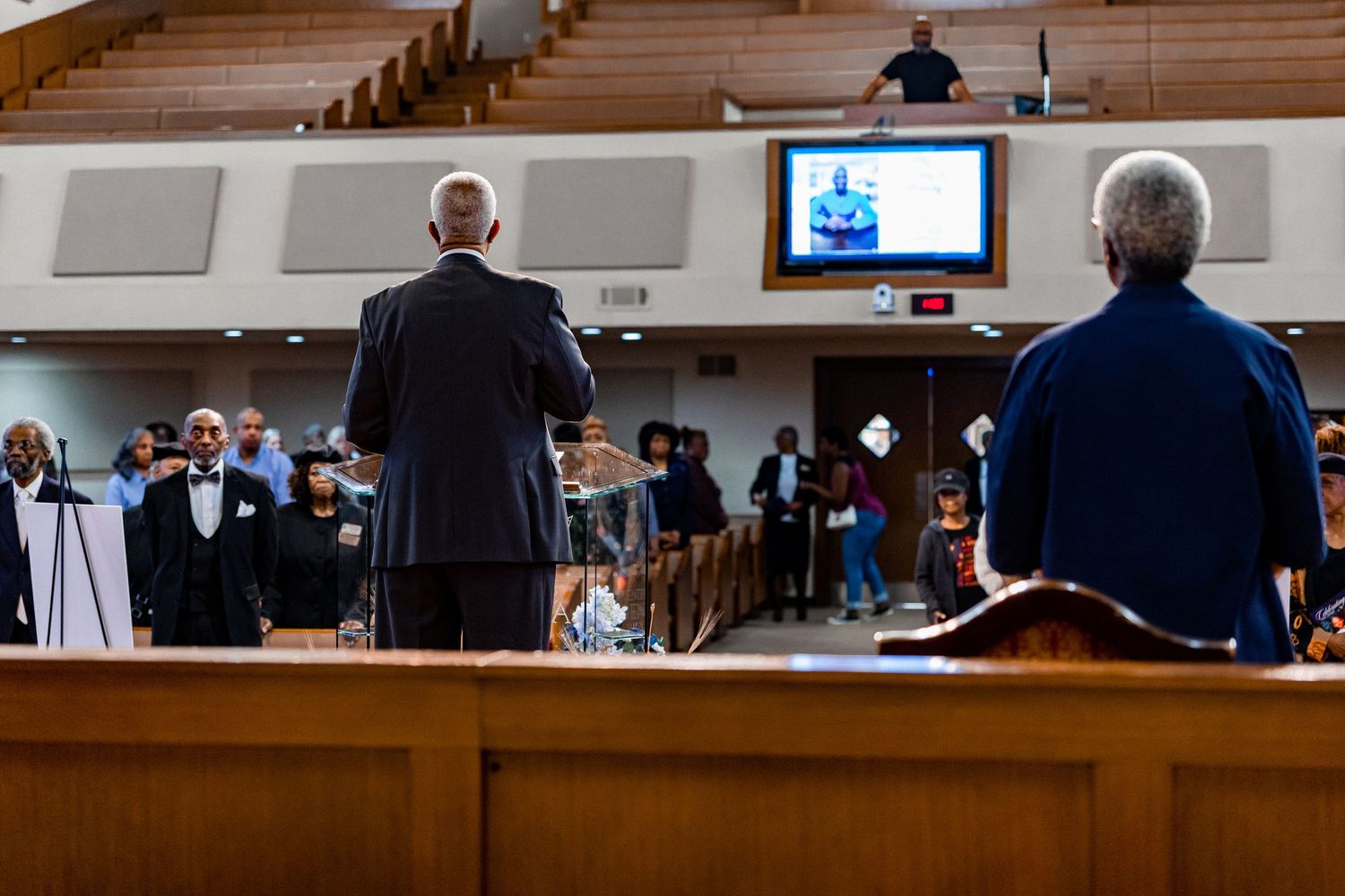 Wide view of church sanctuary during service with podium and American flag.