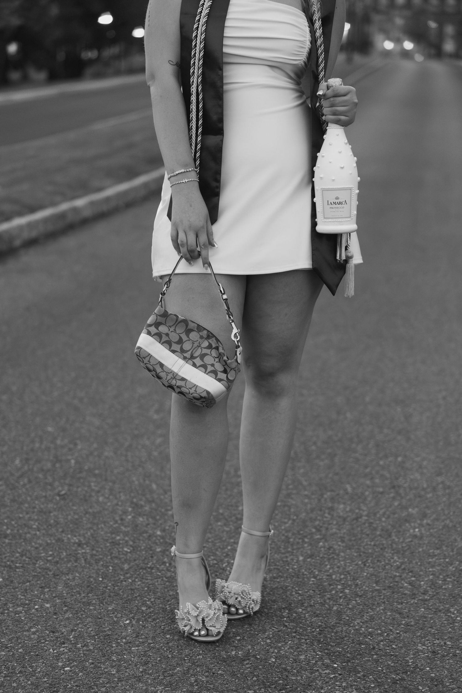 Close-up of sparkly flats and graduation stole against asphalt path.