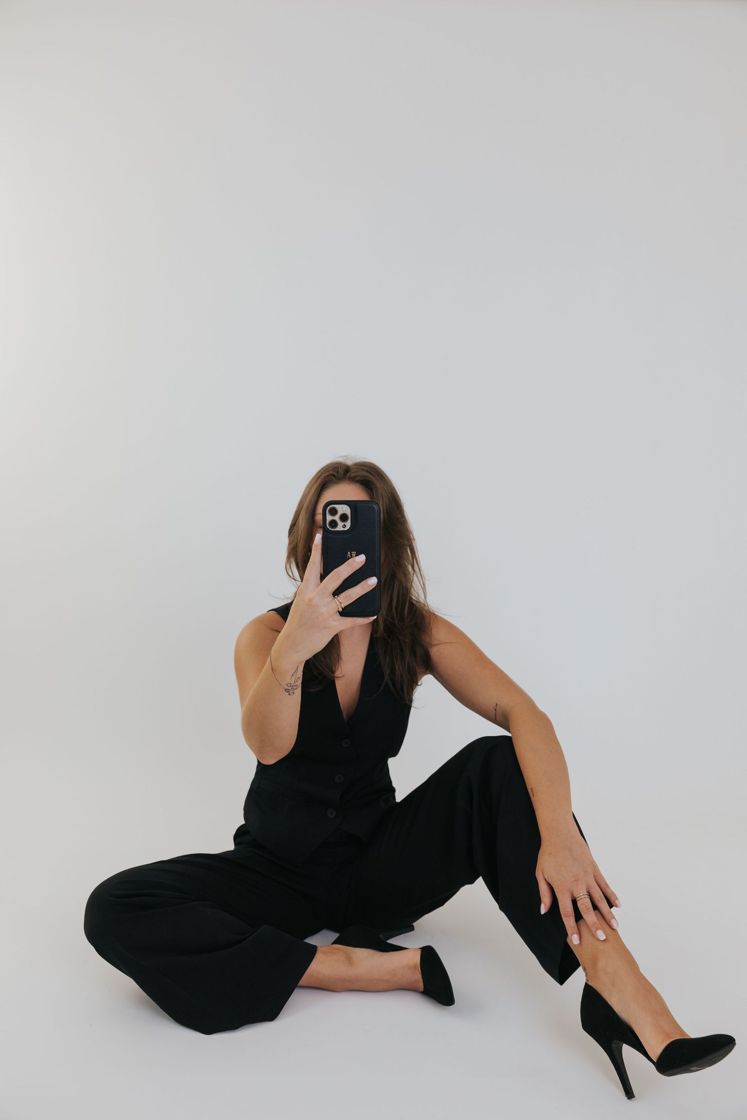 Artistic fashion poses against white backdrop showing person in black outfit and heels on floor.