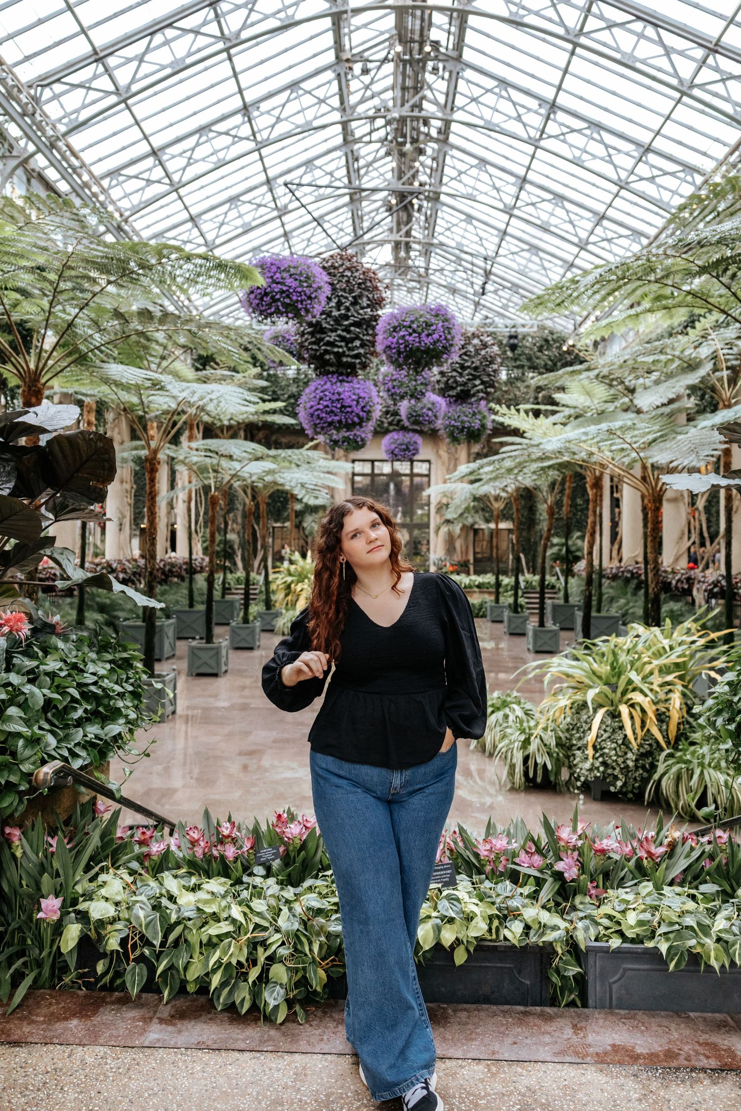 Natural light portrait in conservatory surrounded by exotic plants and flowers.