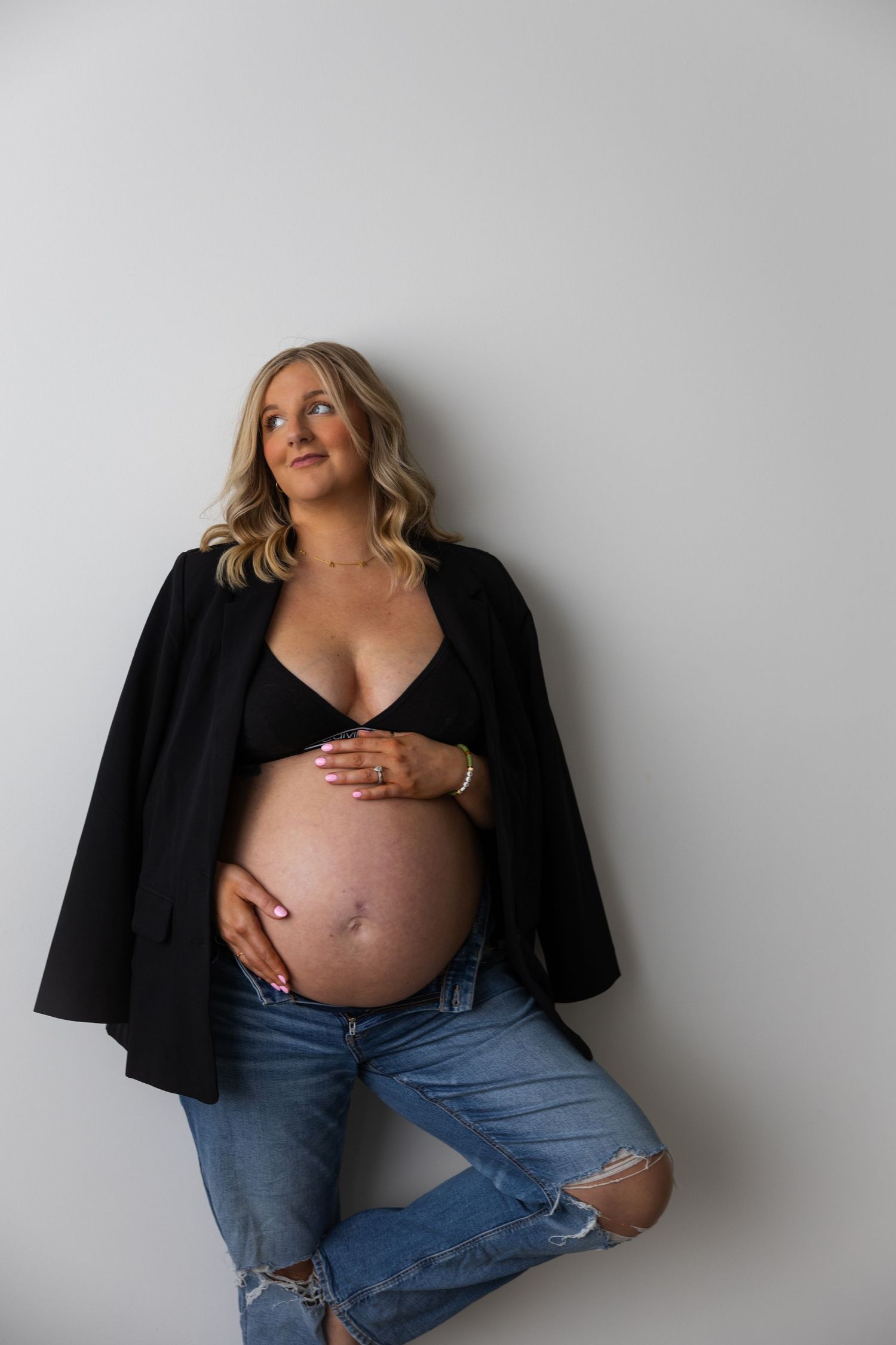 Artistic maternity portraits showing a pregnant woman in jeans and black top.