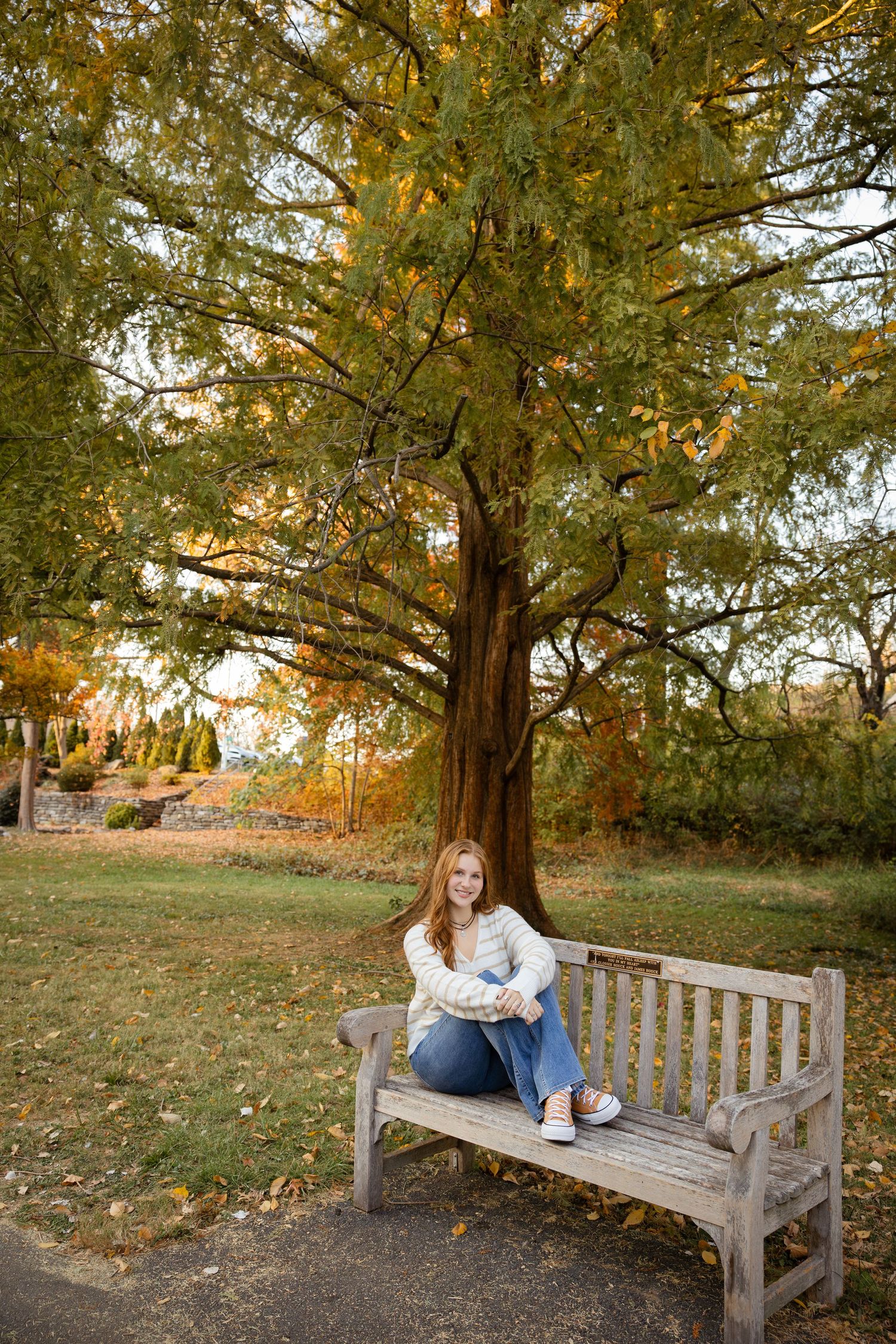 Relaxed poses on a wooden park bench surrounded by fall foliage.