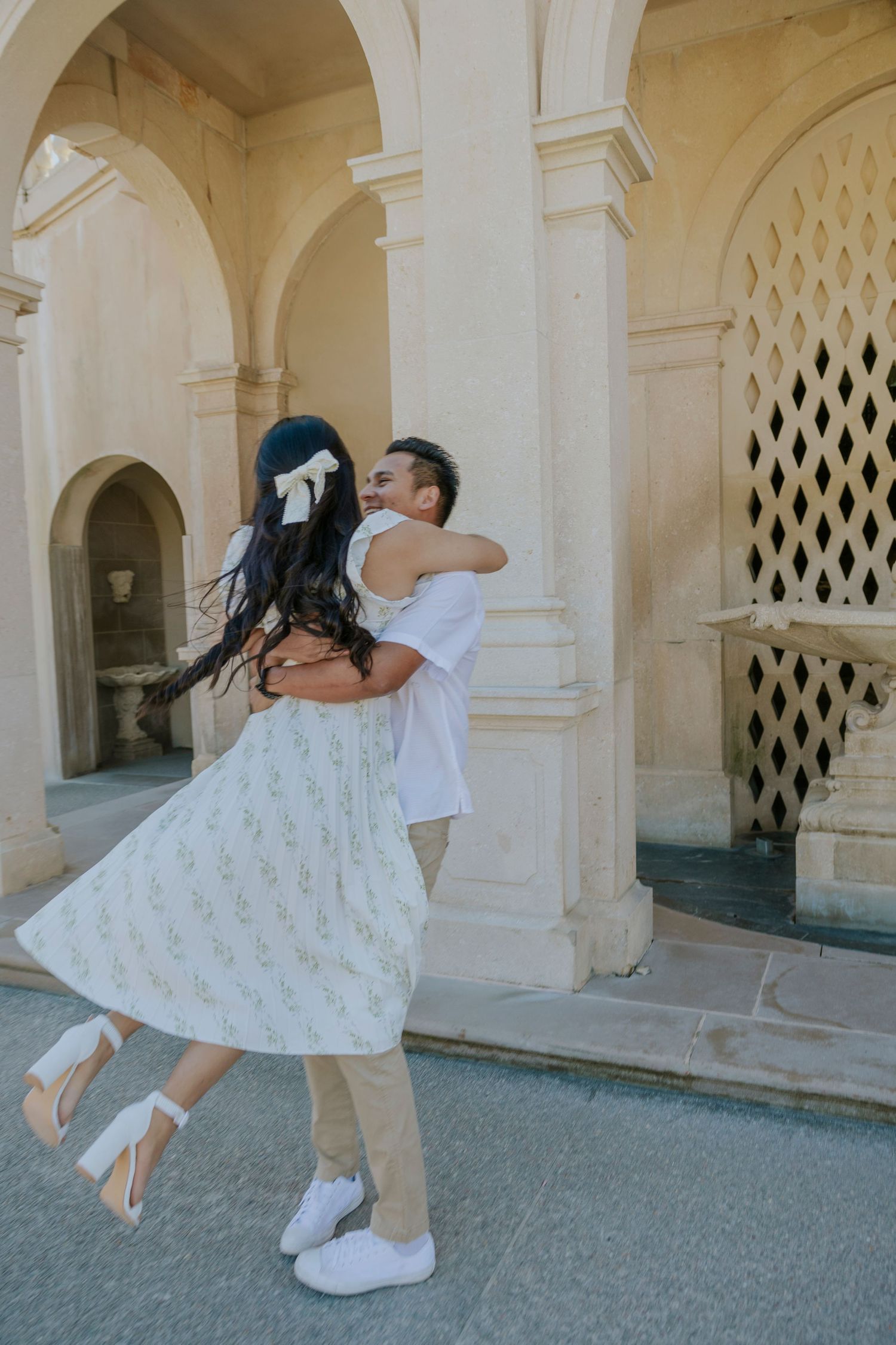 Joyful spinning dance move in front of historic stone colonnade.