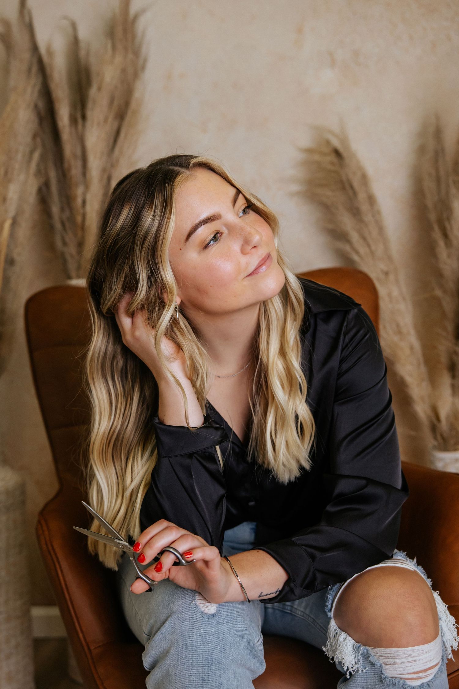 Lifestyle photos on a leather chair with pampas grass decor in the background.