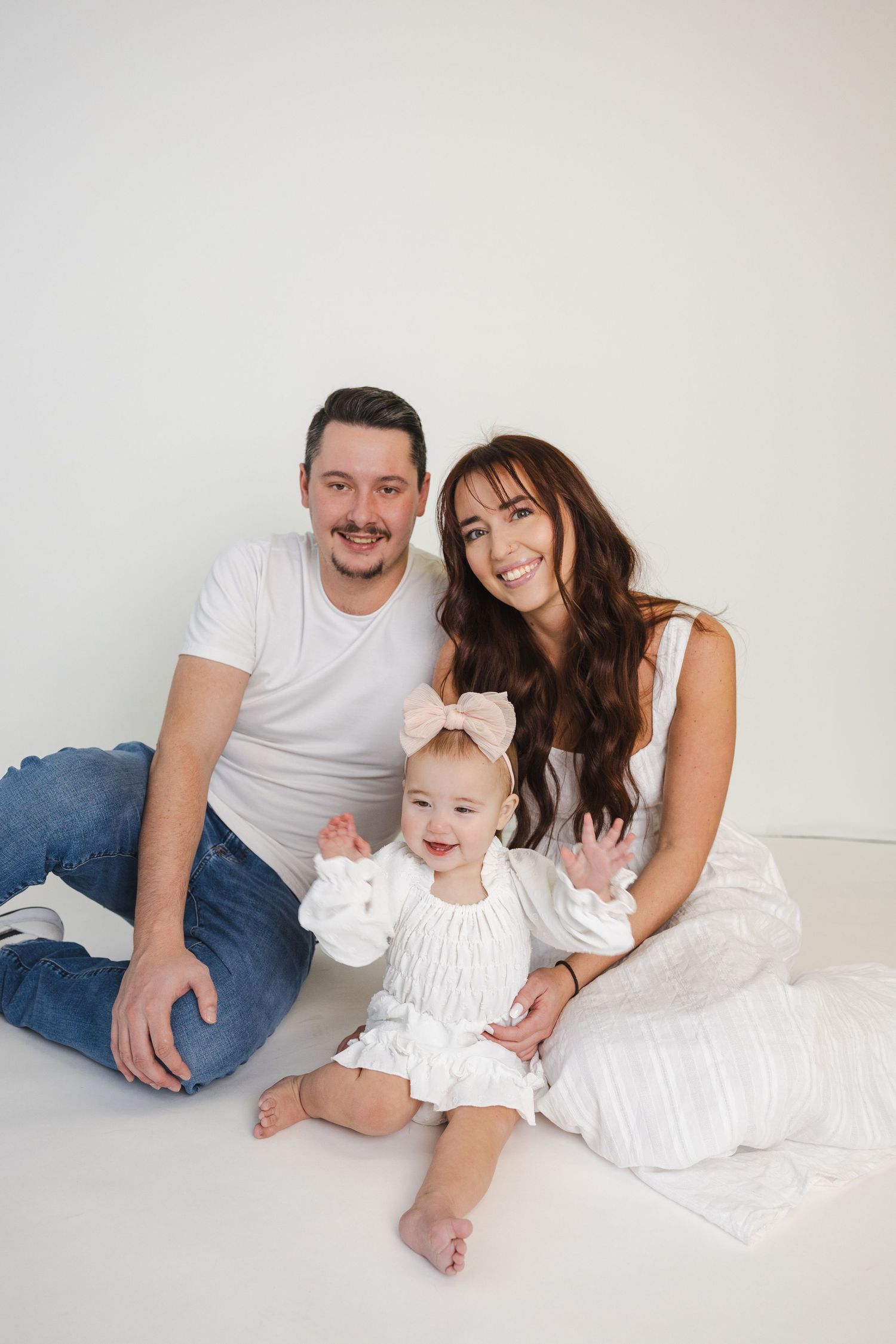 Family lounging together on white floor during casual photo session.