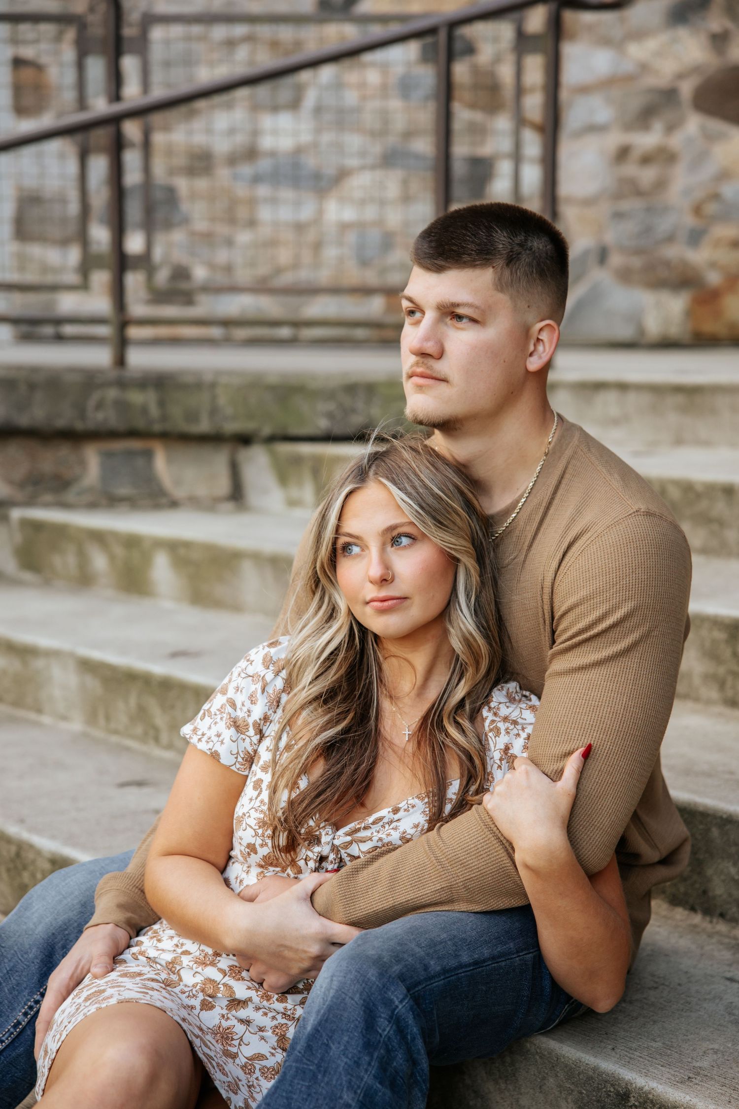 A couple shares an intimate moment while sitting on outdoor concrete steps.